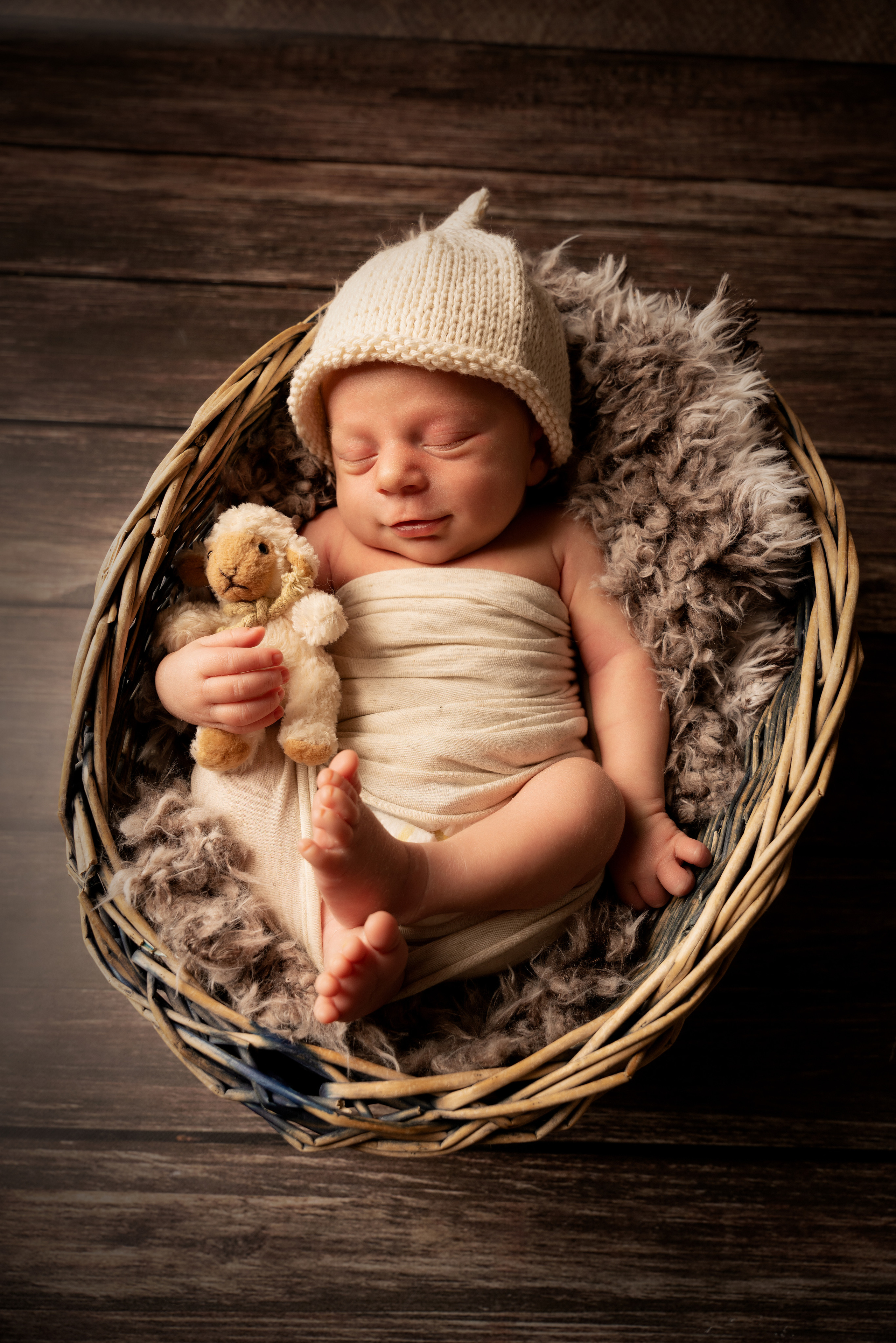 Baby umarmt ein weißes Plüschschaf