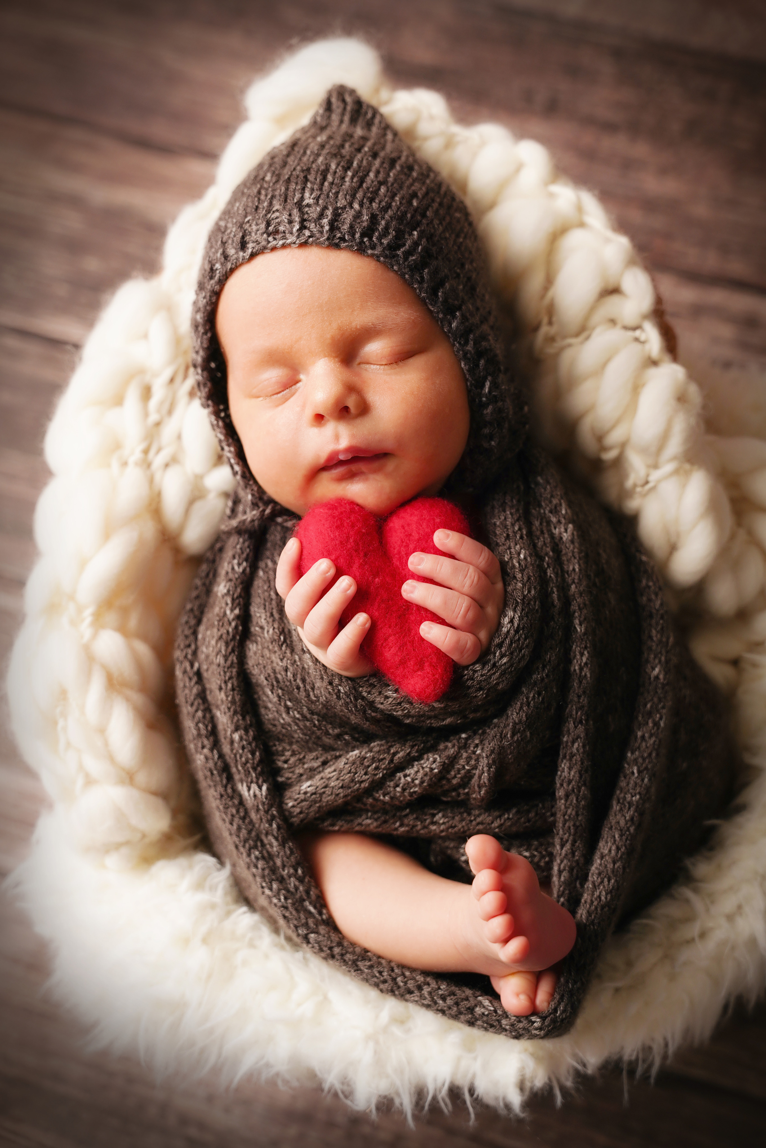 Baby drückt ein Herz aus Filz fest in ihre Handflächen