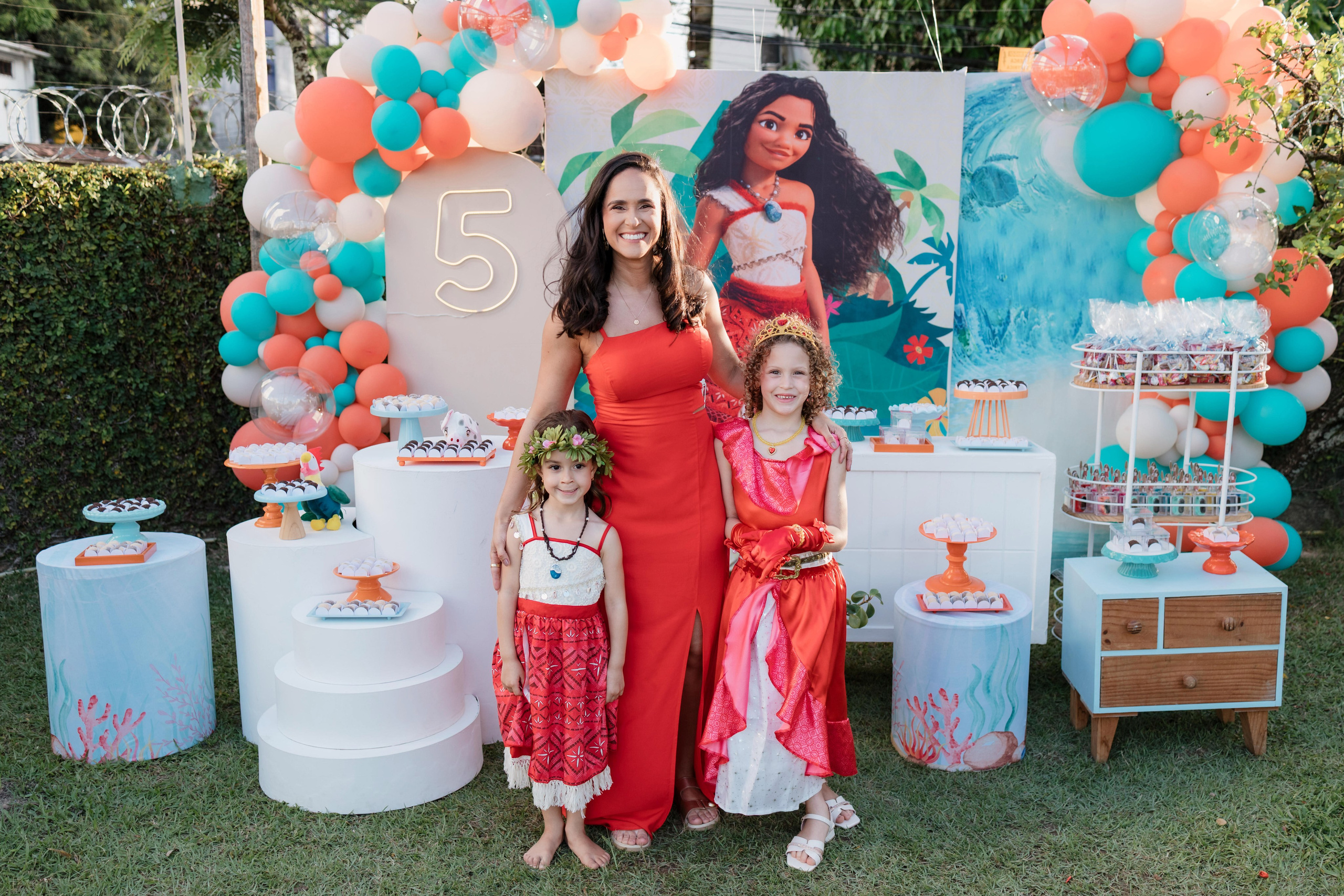 Mãe e filhas posando na decoração da festa infantil