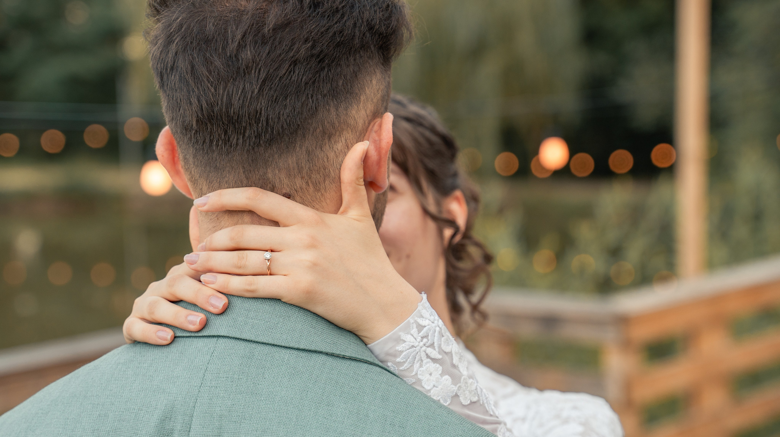 Detaliu mână mireasă pe gâtul mirelui, inel de logodnă cu diamant, portret de cuplu la apus incadru.ro.