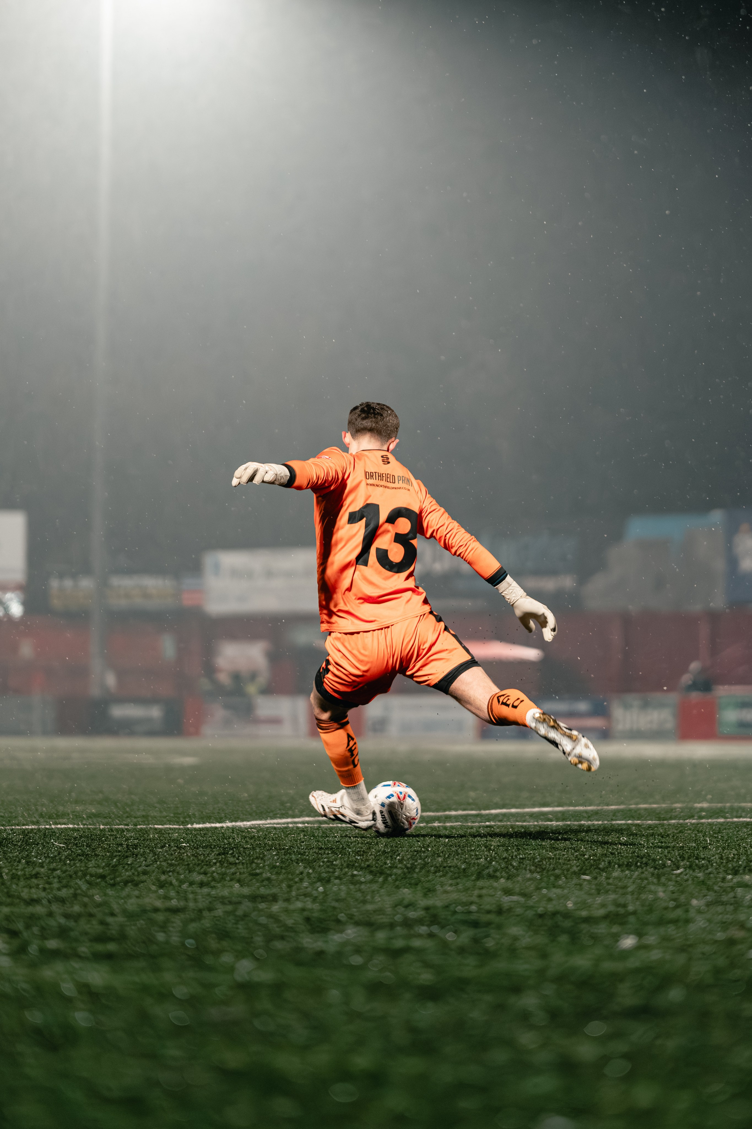 Jenson Kilroy of Alvechurch kicks the ball upfield in heavy rain during the Birmingham Senior Cup match at The Lamb Ground, Tamworth, Feb 3 2026.
