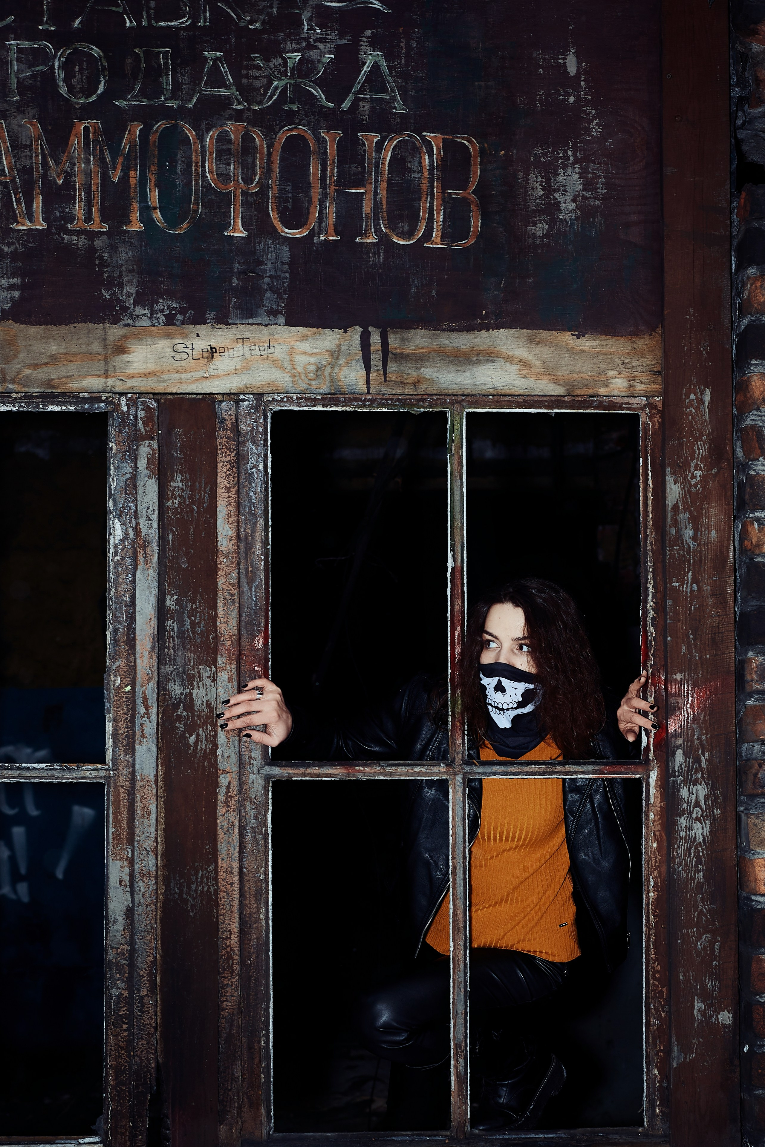 Уличная фотосесия красивая девушка зимой в заброшенной промзоне выглядывает из окна