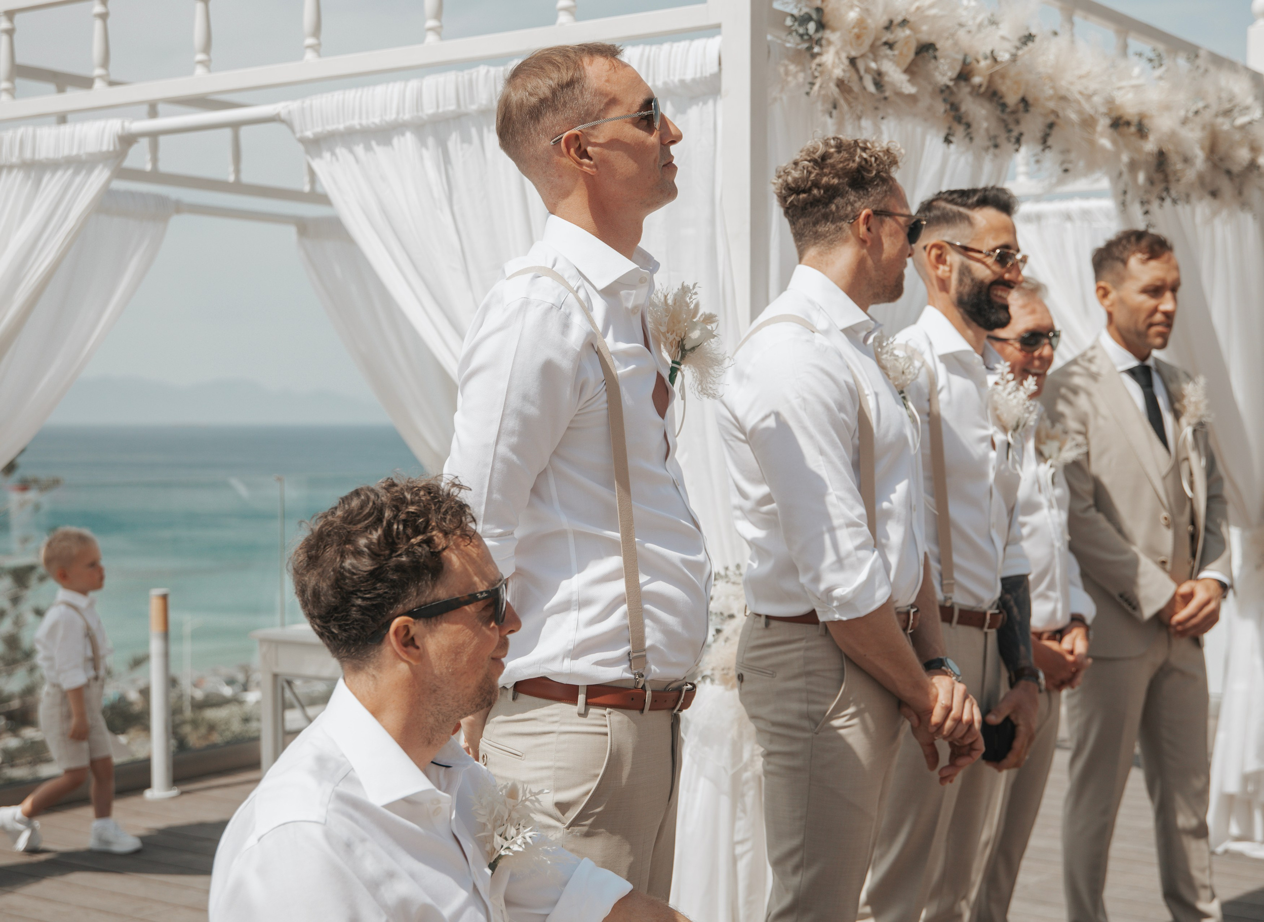 Groom smiling as he waits for his bride at the entrance of the wedding reception with his mates in Sheraton hotel Rhodes, Greece