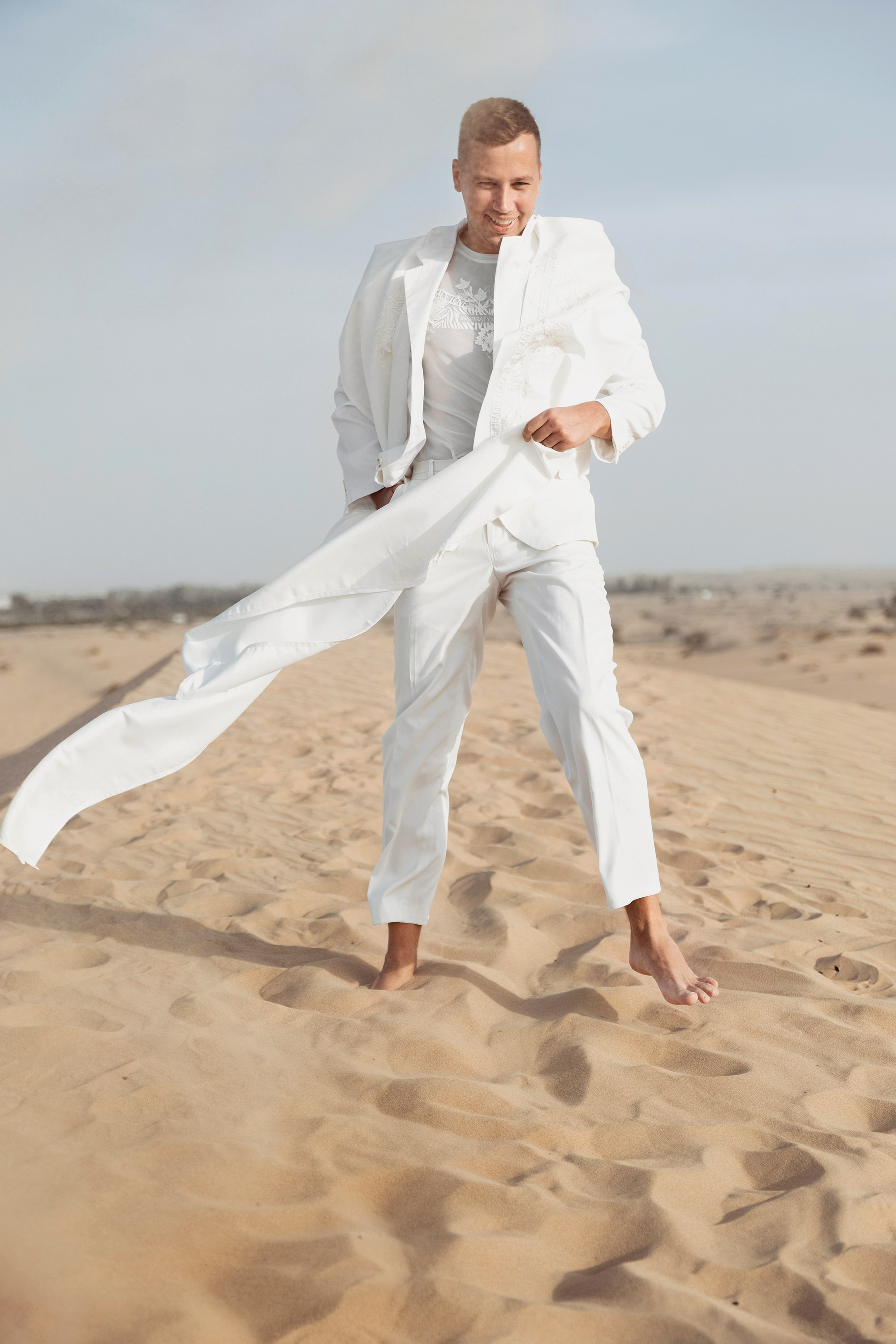 Groom is playing with the sand in a Dubai desert