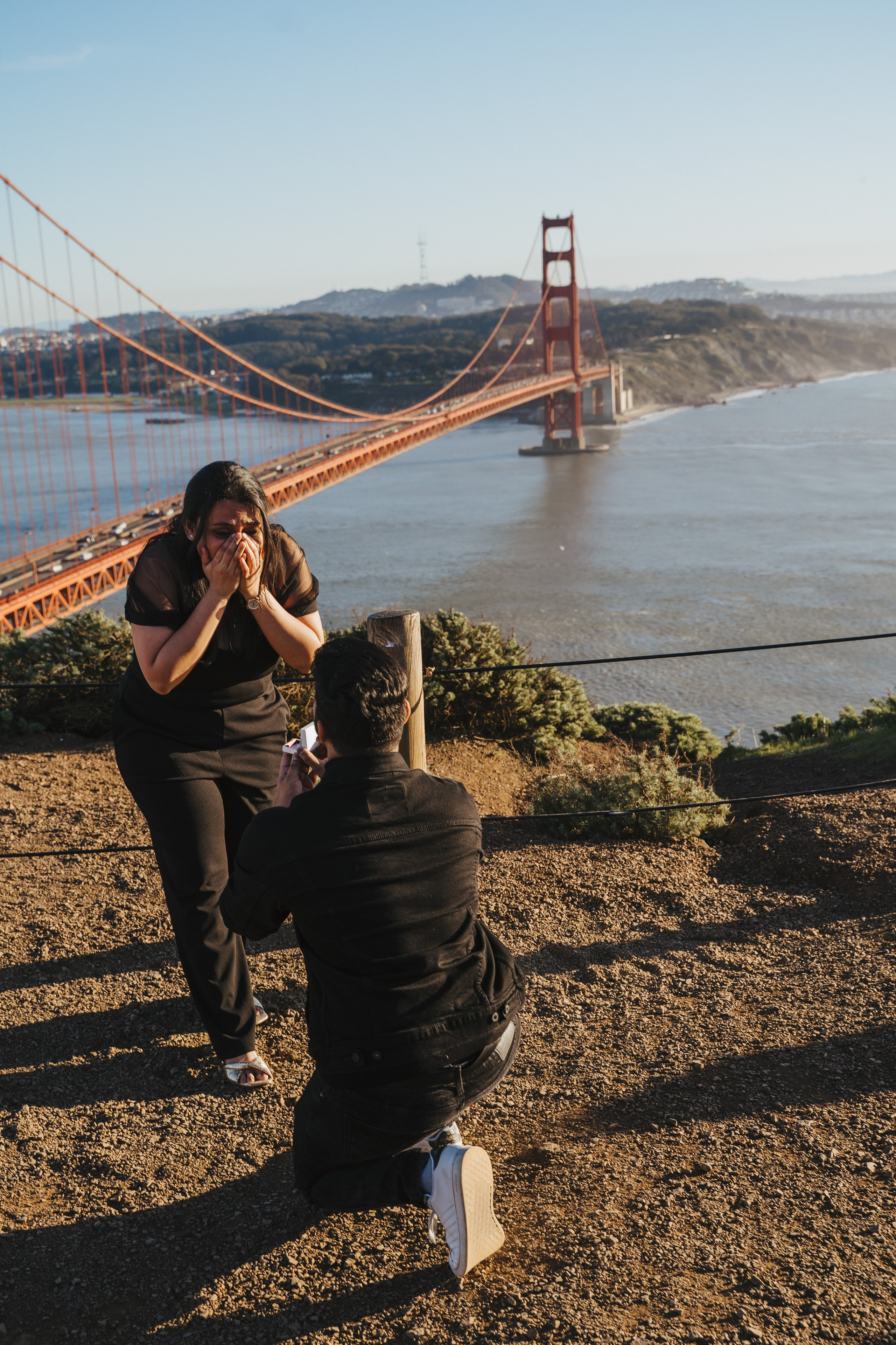 Proposal.  Overlooking the golden San Franisco Bridge sunset with a couple. Photographer Video. 