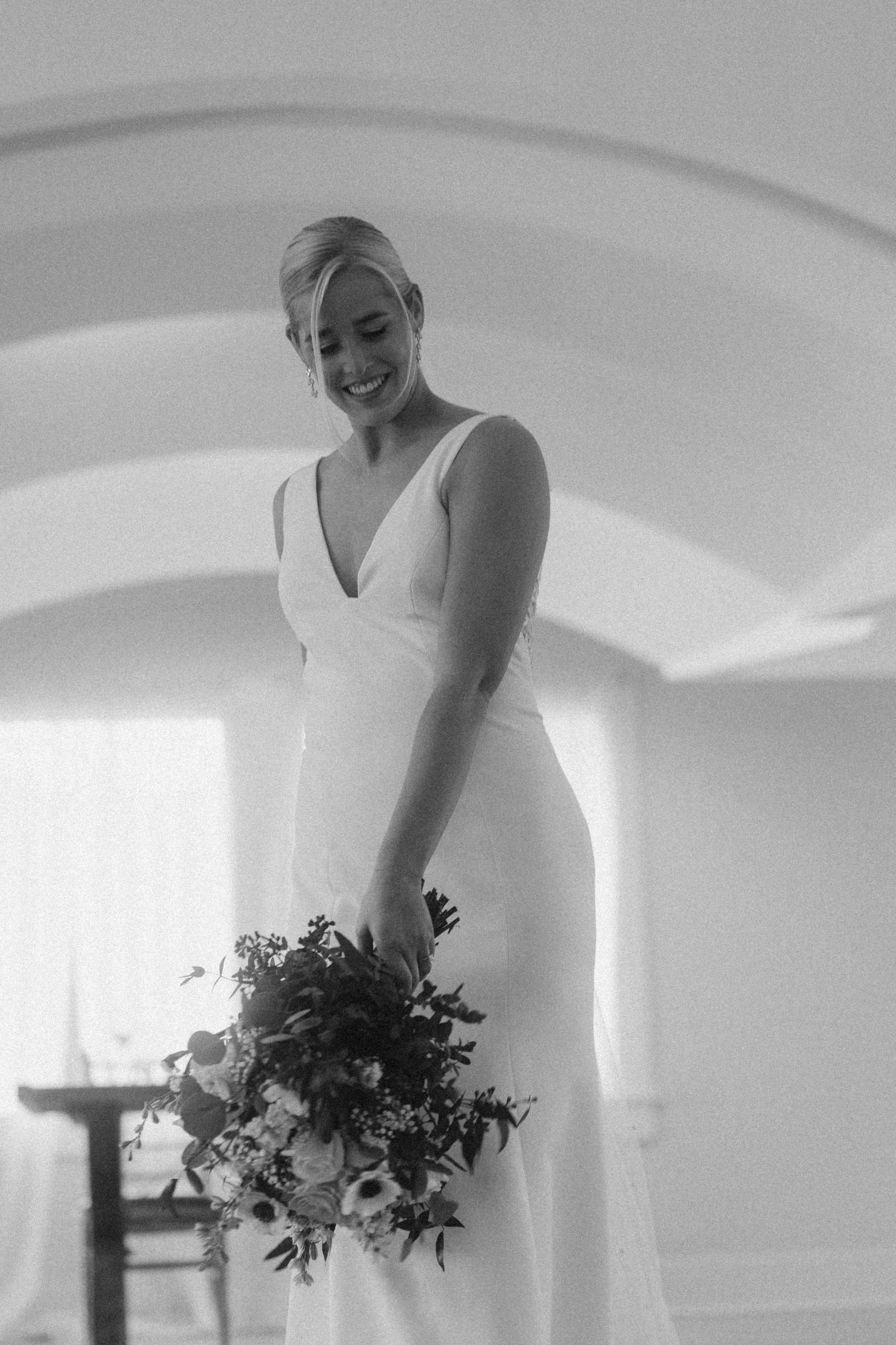 Bride holding flowers near Lake George gazebo.