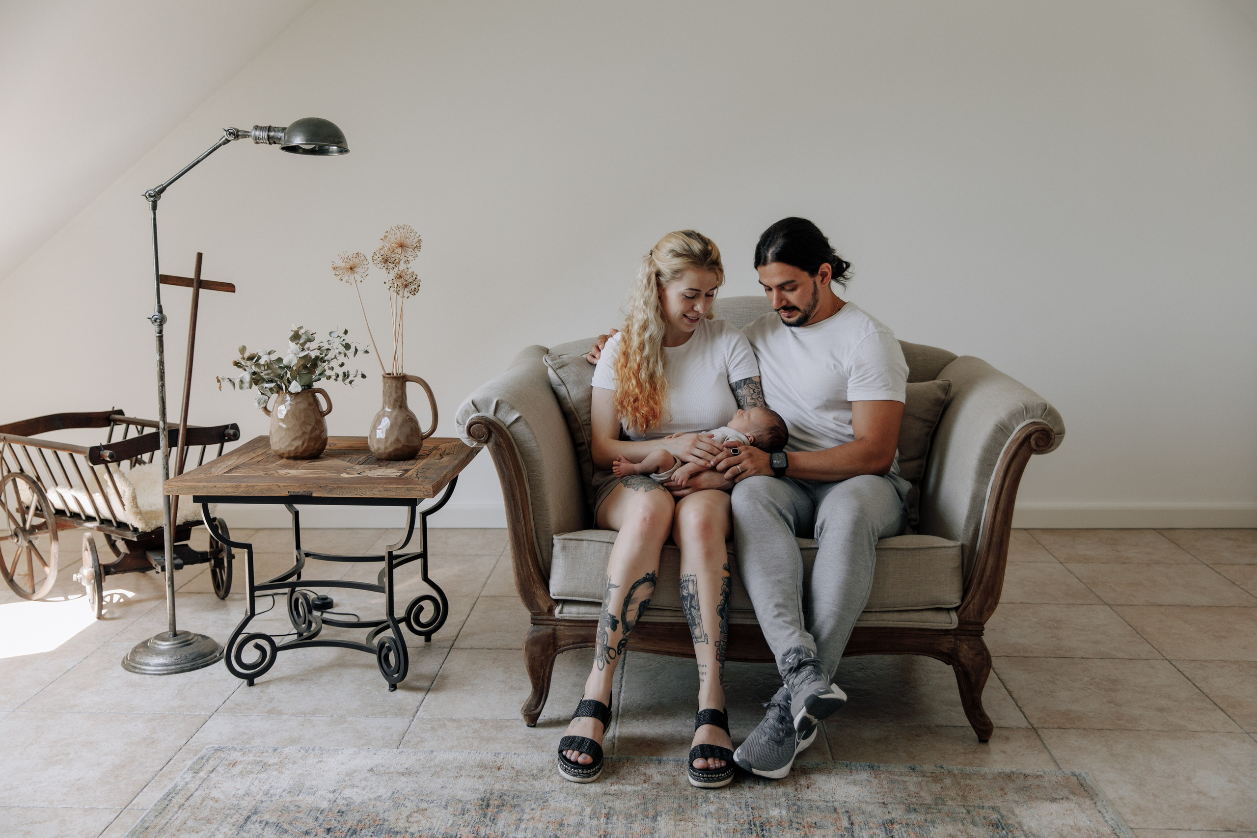 Eltern sitzen mit ihrem Baby auf dem Schoß in einem schönen Interieur. Ein warmer und liebevoller Familienmoment.