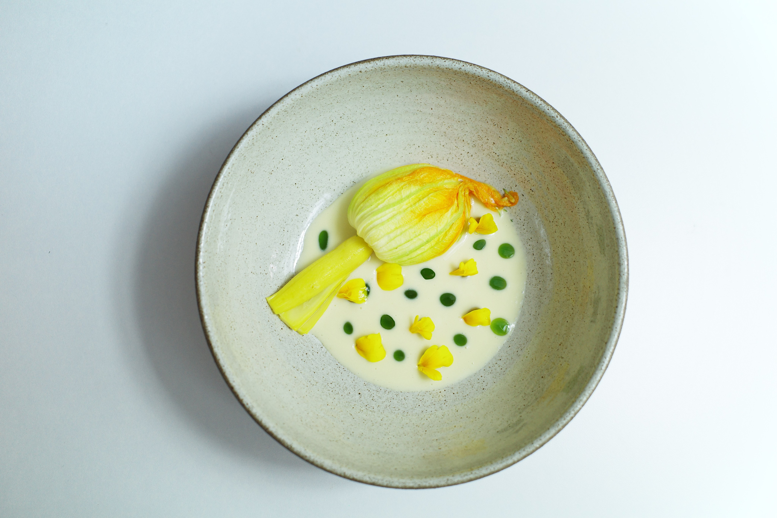 “Stuffed zucchini flower with homemade curd and Cremetta, fresh herbs and lemon zest, served with beurre blanc sauce.”