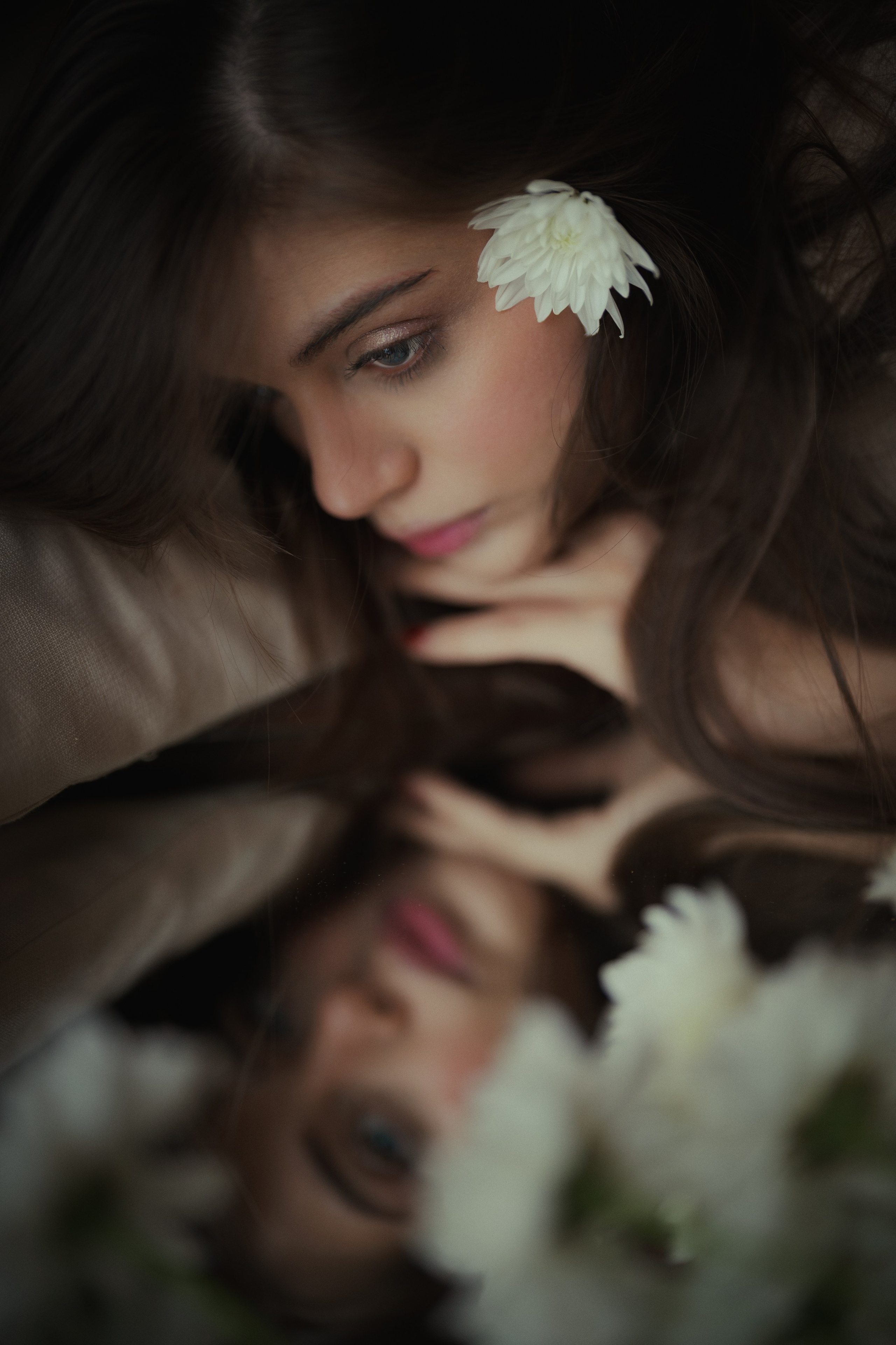 Dreamy close-up mirror portrait with a white flower, soft reflections and cinematic shallow focus, photographed by Mehran Hadad.