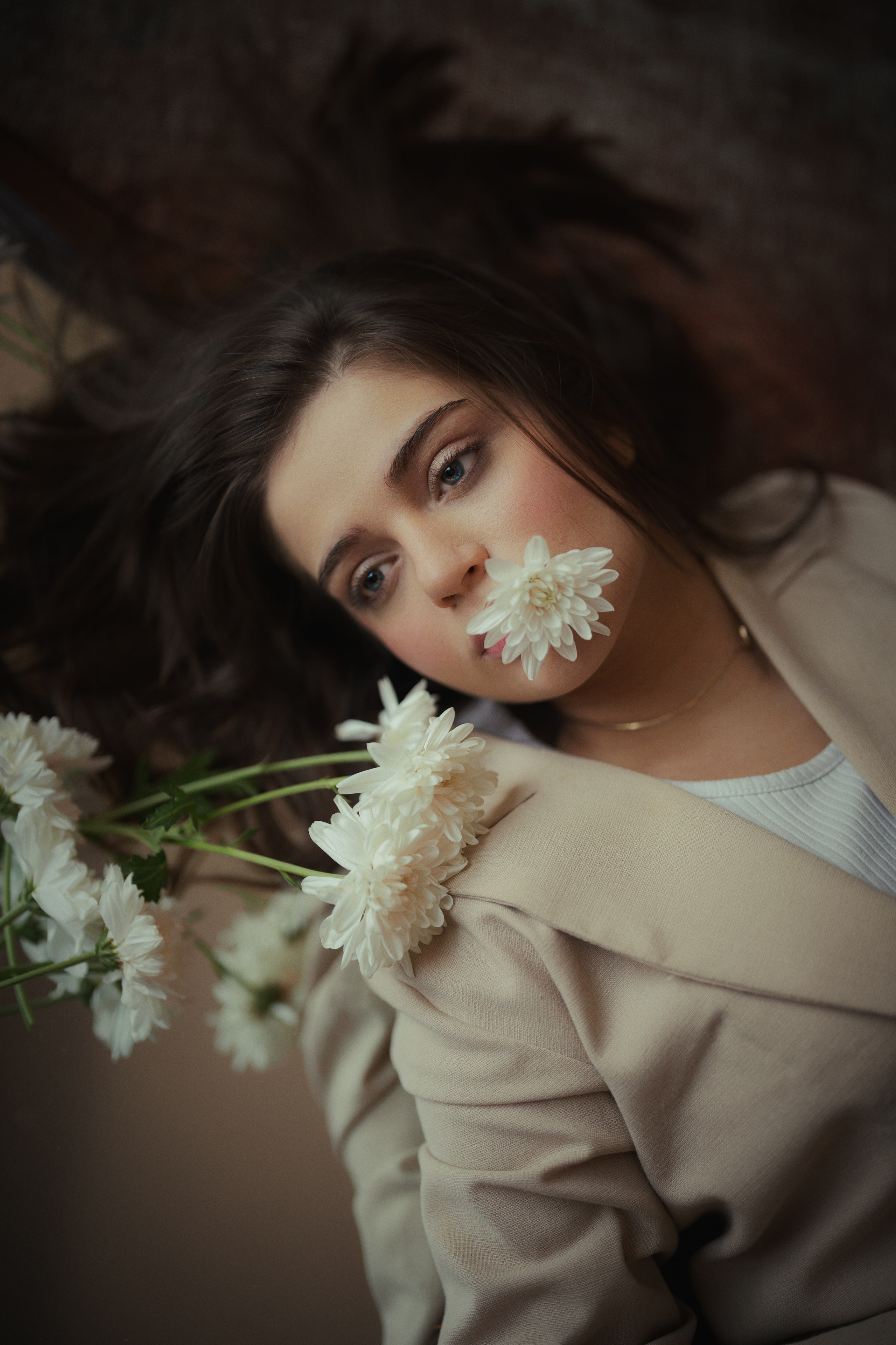 Artistic floral portrait of a woman in a beige suit with white flowers, captured in warm cinematic tones by Mehran Hadad.