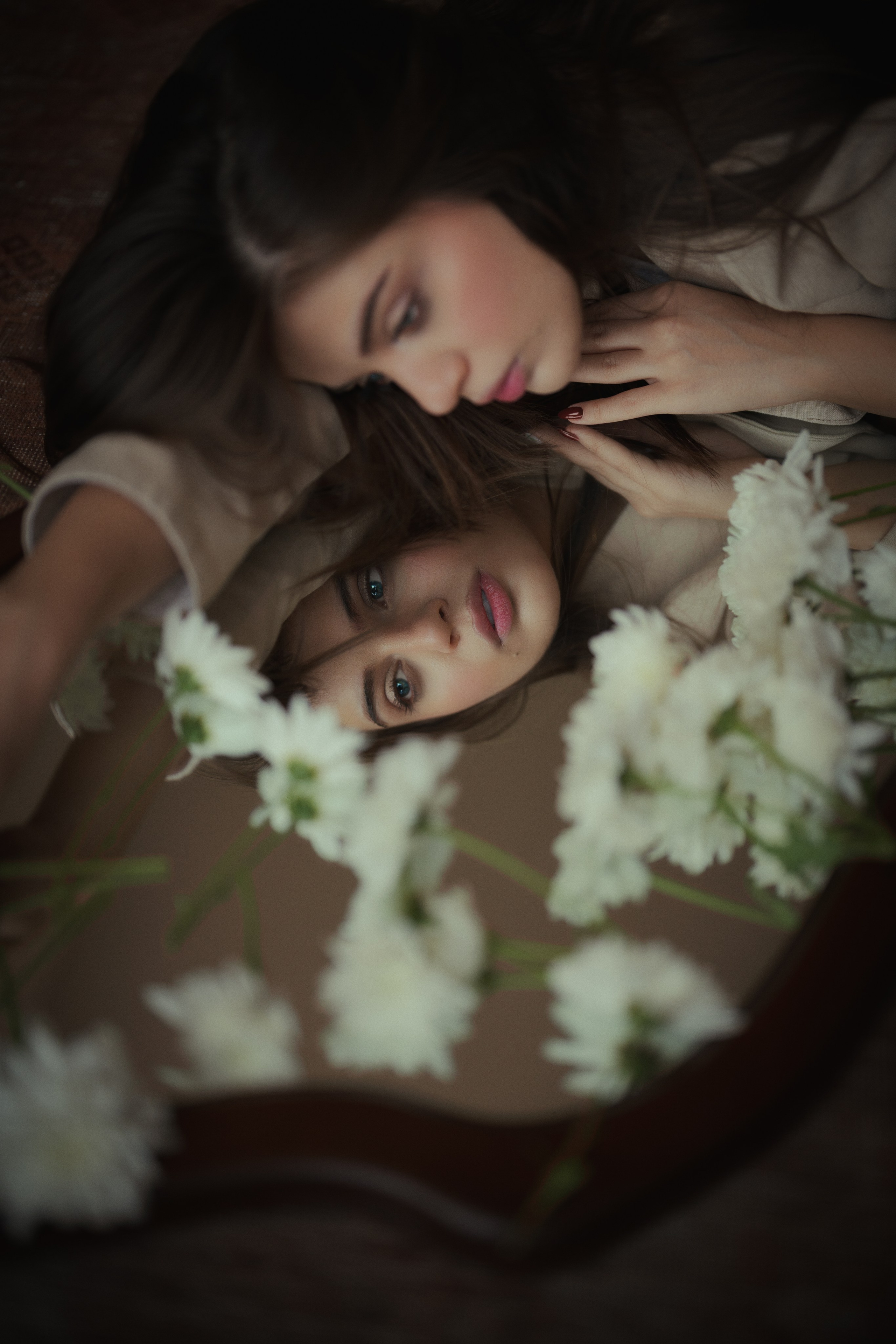 Artistic mirror portrait with layered reflections and white flowers, photographed by Mehran Hadad in a soft cinematic editorial style.