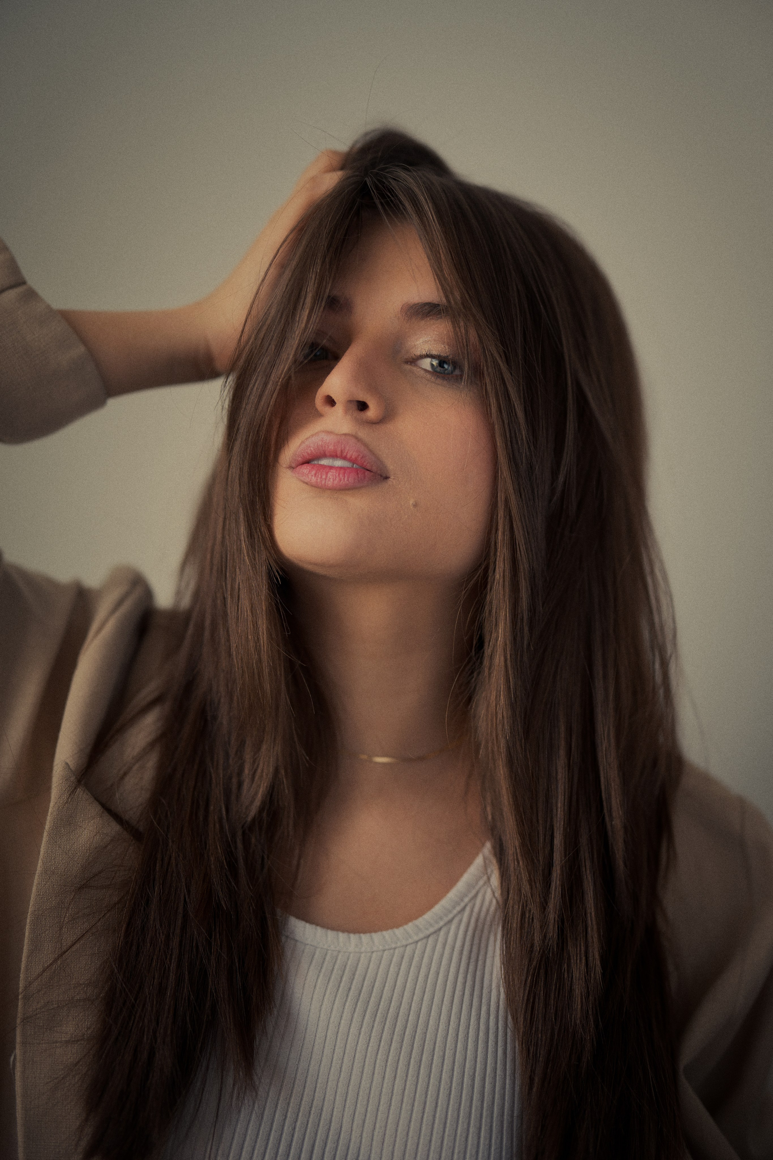 Cinematic portrait of Forouq Mohamadi by Mehran Hadad featuring long brown hair, a beige blazer and an elegant pose captured in warm natural light.