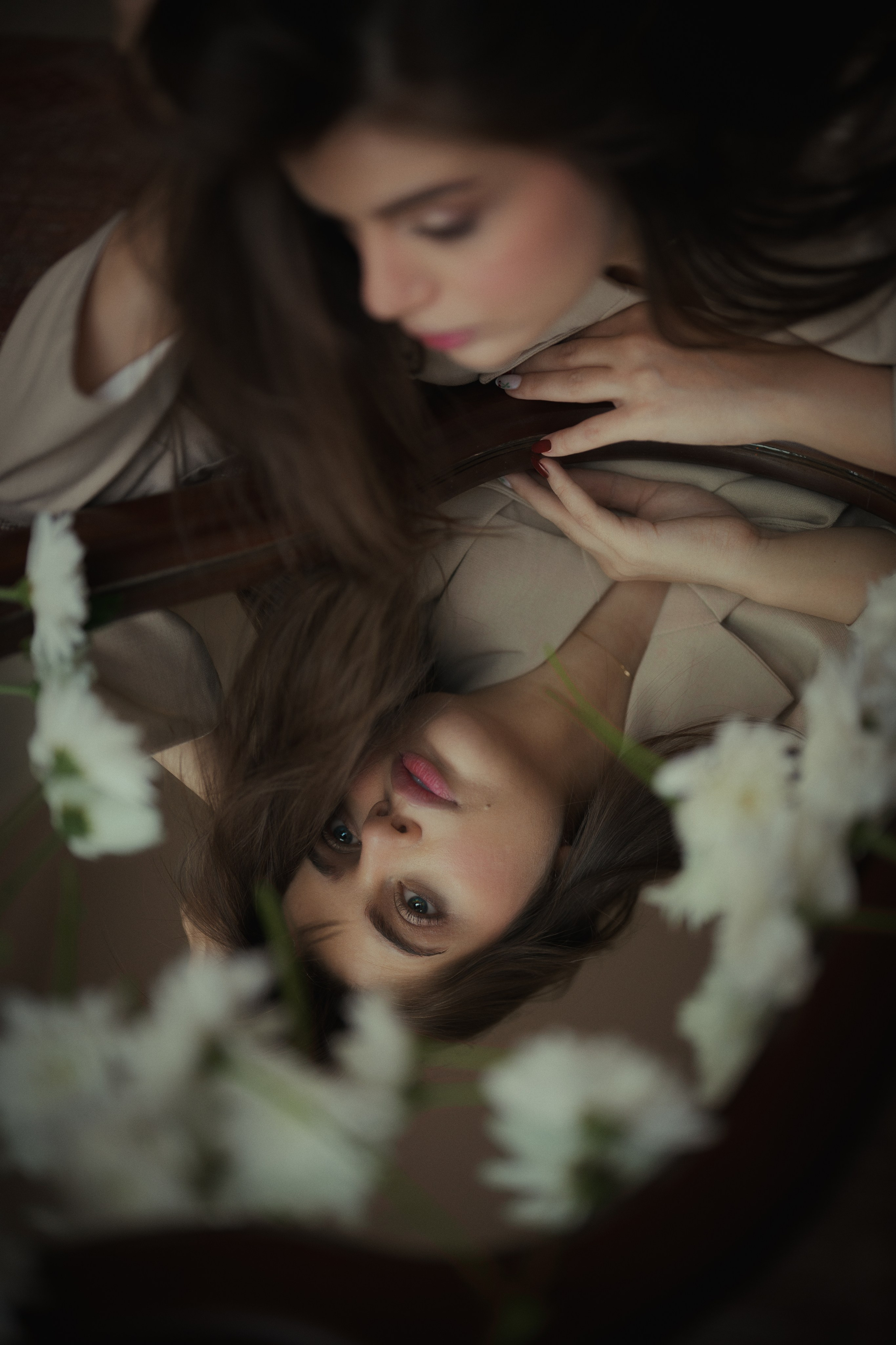 Creative reflection portrait of a woman surrounded by white flowers, captured with soft focus and cinematic warm tones by Mehran Hadad.