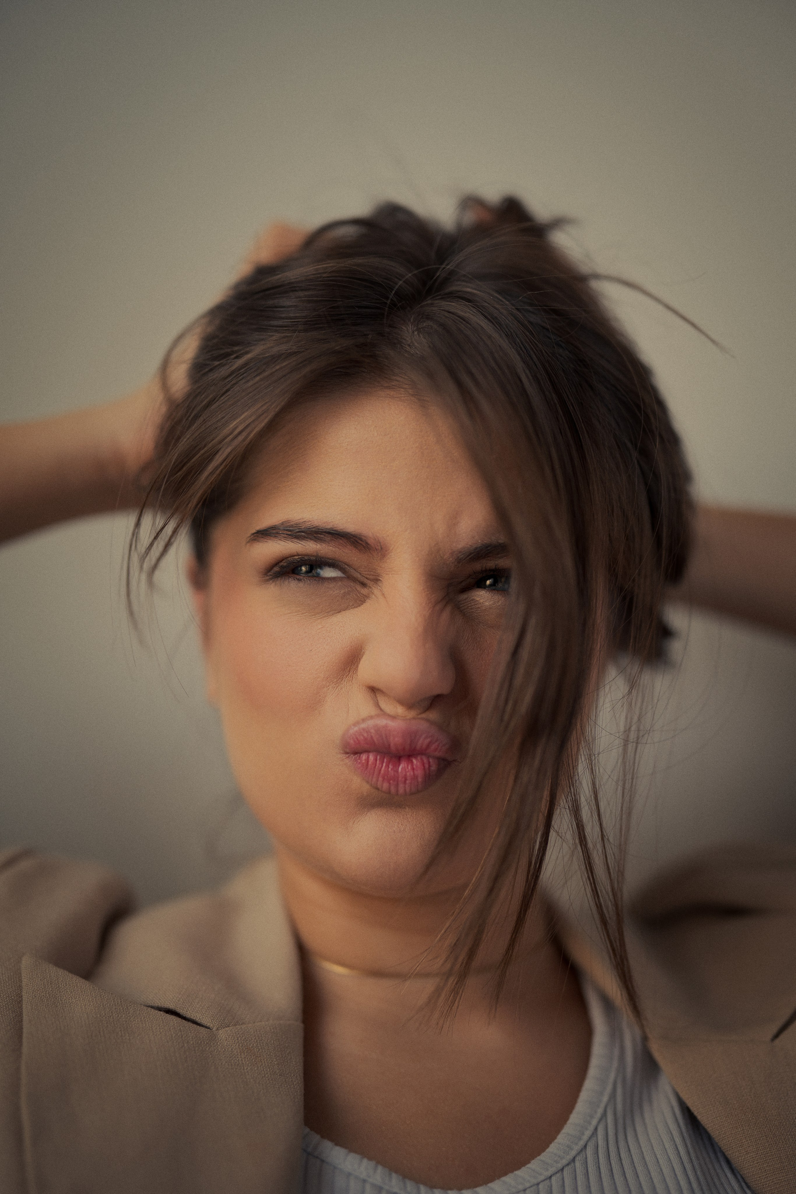 Expressive close-up female portrait by Mehran Hadad featuring Forouq Mohamadi with loosely tied brown hair and playful editorial styling.