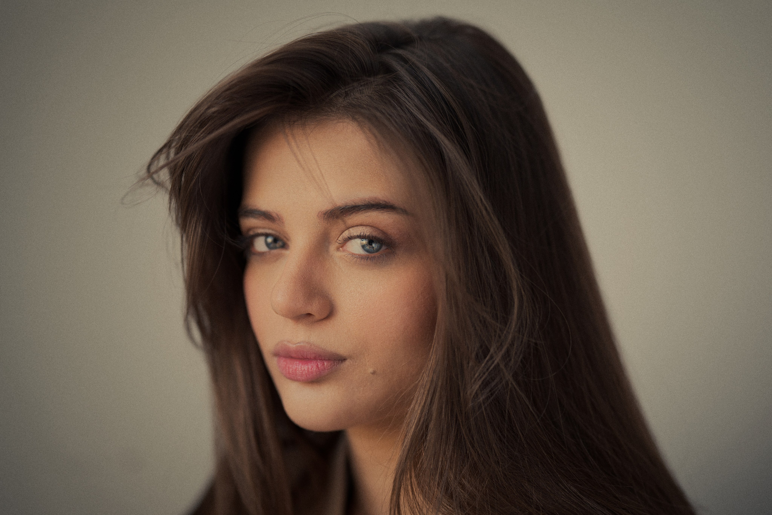 Cinematic close-up portrait of Forouq Mohamadi by Mehran Hadad featuring long brown hair, blue eyes and a natural expression, captured in soft warm light with neutral tones.