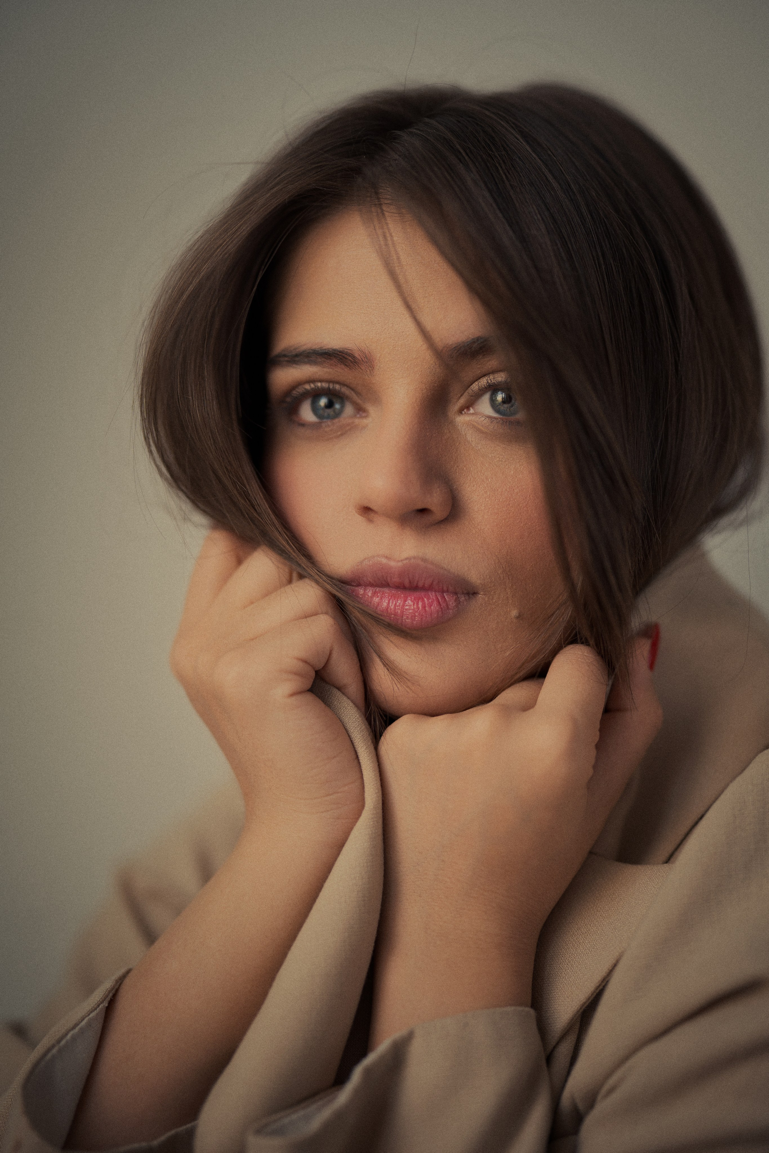 Cinematic close-up portrait photography by Mehran Hadad featuring Forouq Mohamadi with an expressive gaze, brown hair and soft beige styling.