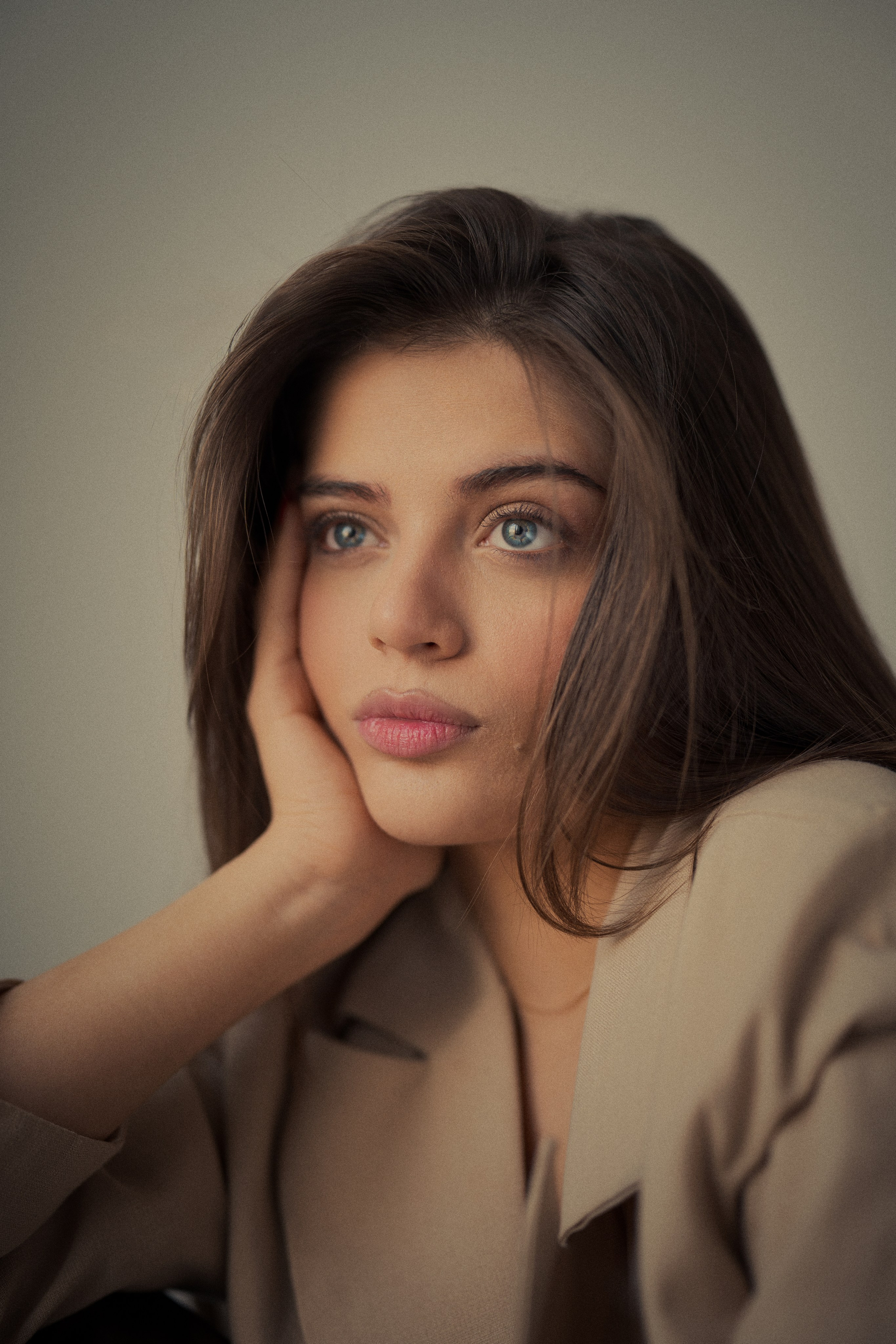 1. Fine art female portrait photography by Mehran Hadad featuring Forouq Mohamadi resting her face on her hand with long brown hair and warm neutral tones.
