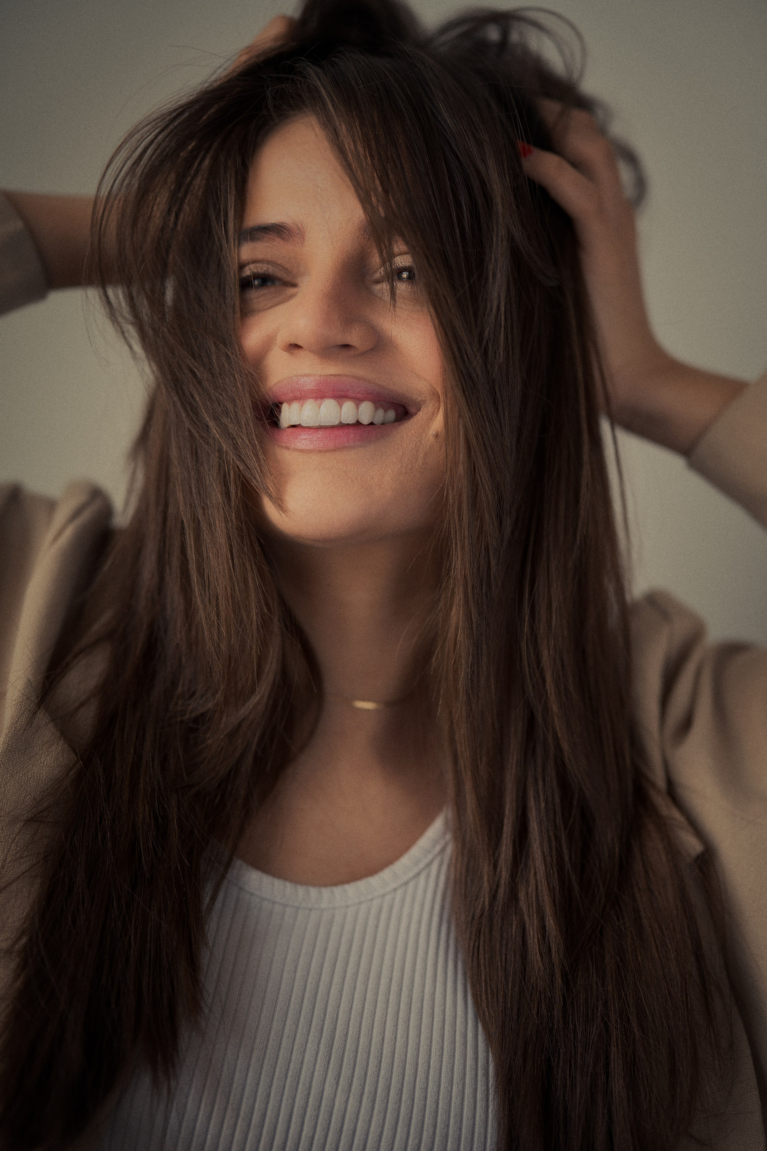 Lifestyle female portrait photography by Mehran Hadad featuring Forouq Mohamadi smiling with tousled brown hair and a beige blazer in warm soft light.