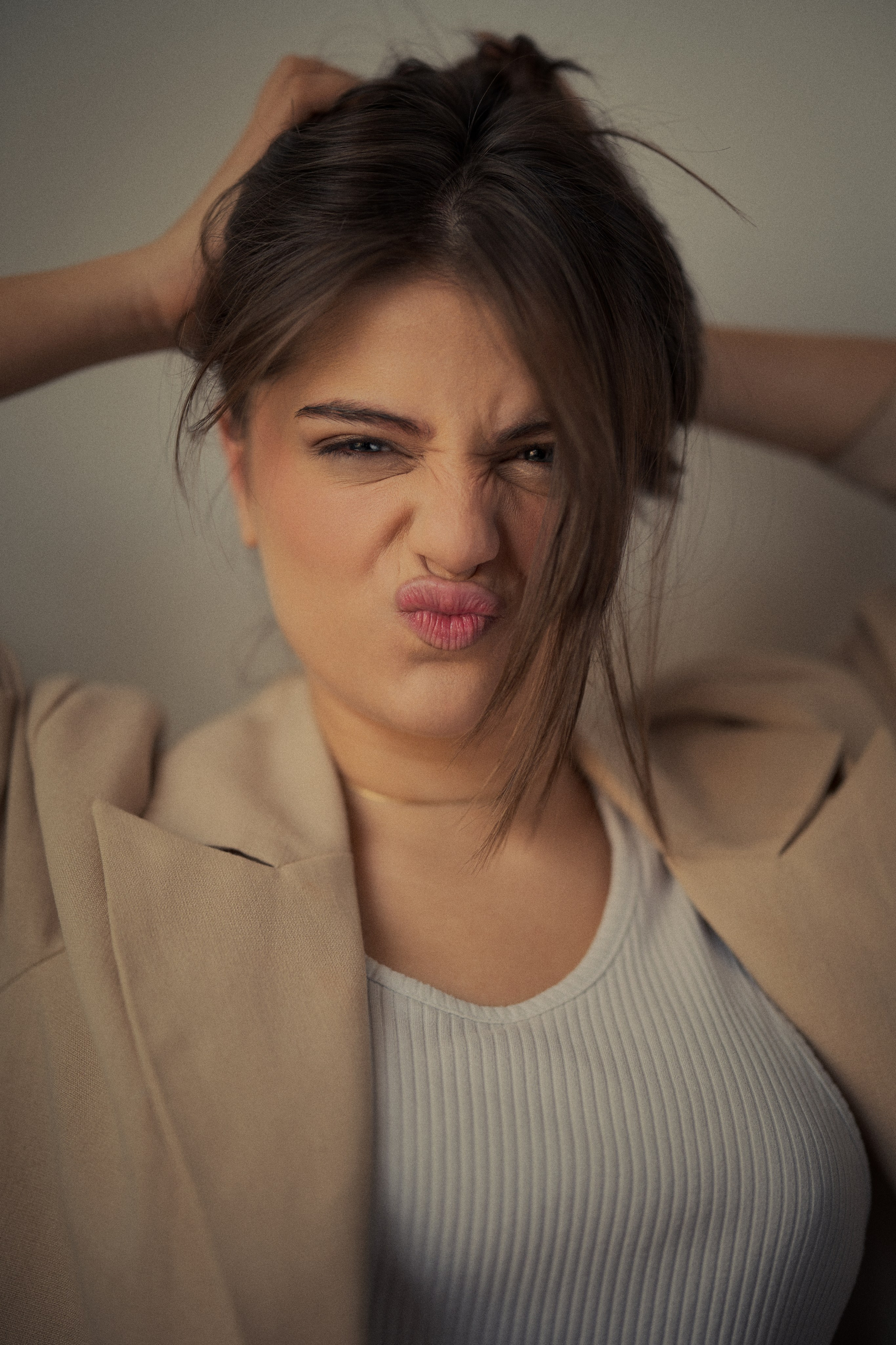 Playful portrait photography by Mehran Hadad featuring Forouq Mohamadi making a spontaneous expression while styling her brown hair in warm soft light.
