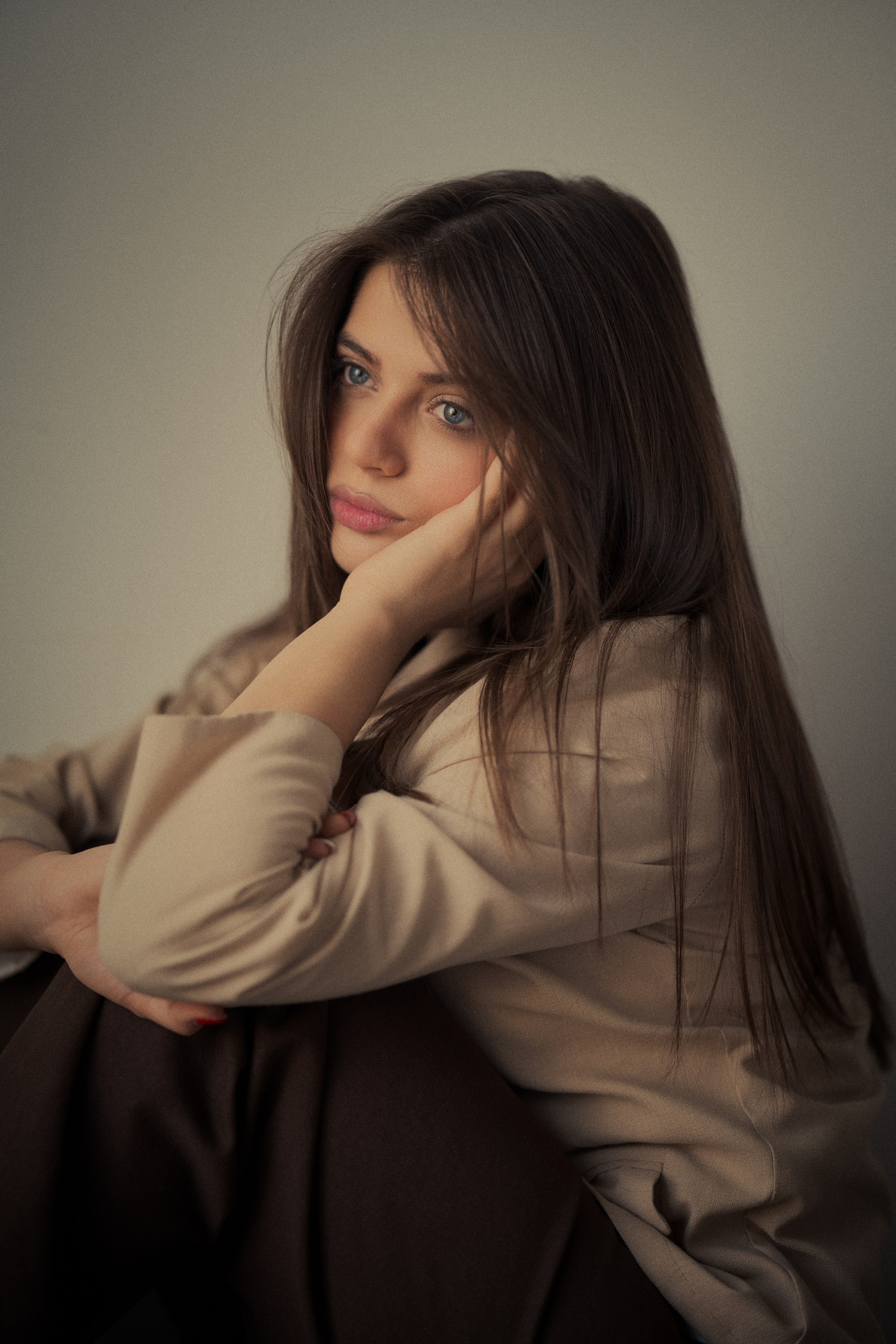 Cinematic seated portrait of Forouq Mohamadi by Mehran Hadad featuring long brown hair, a beige blazer and an intimate relaxed pose in soft light.