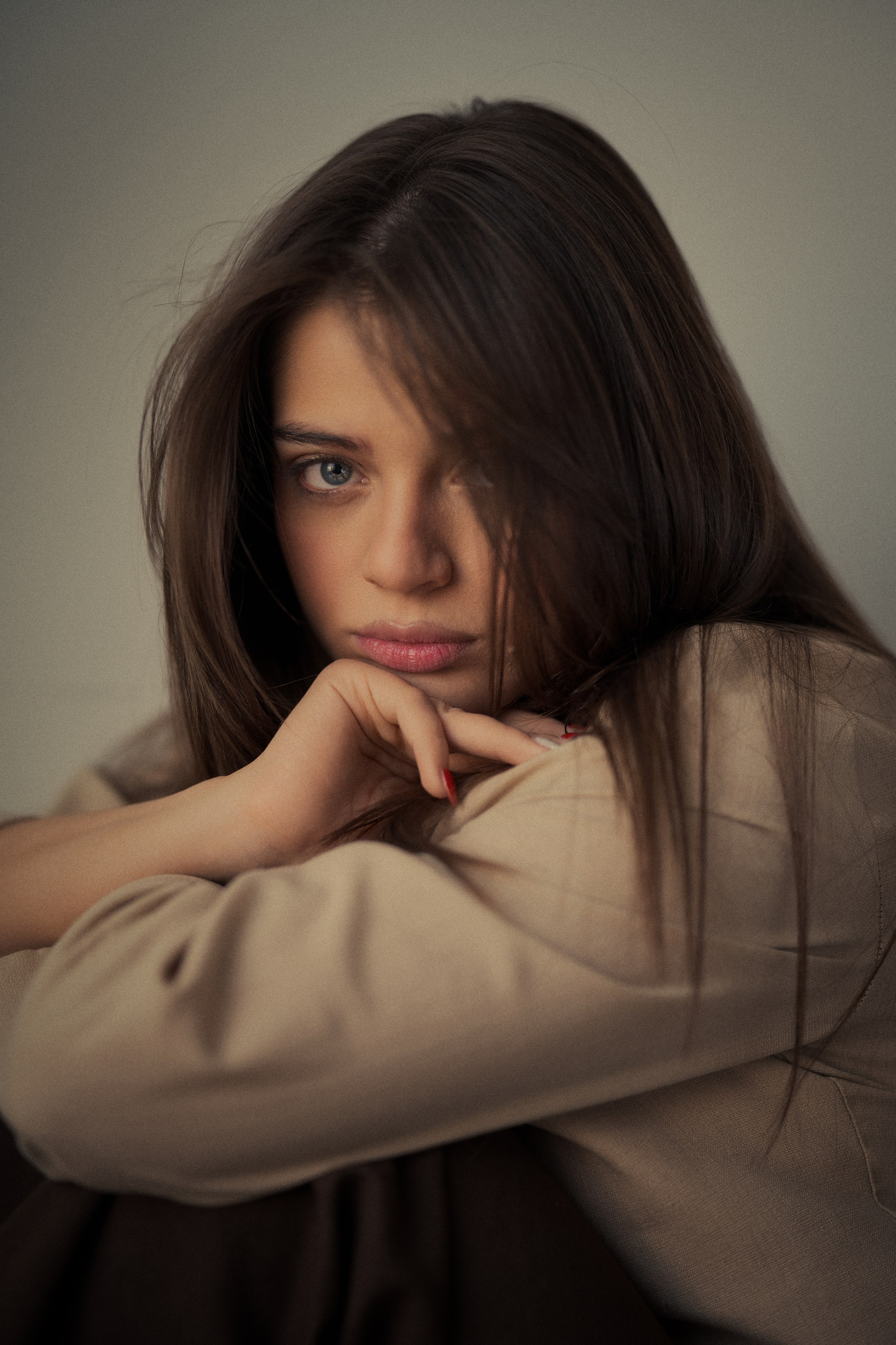 Moody female portrait photography by Mehran Hadad featuring Forouq Mohamadi resting on her arms with long brown hair and soft cinematic lighting.
