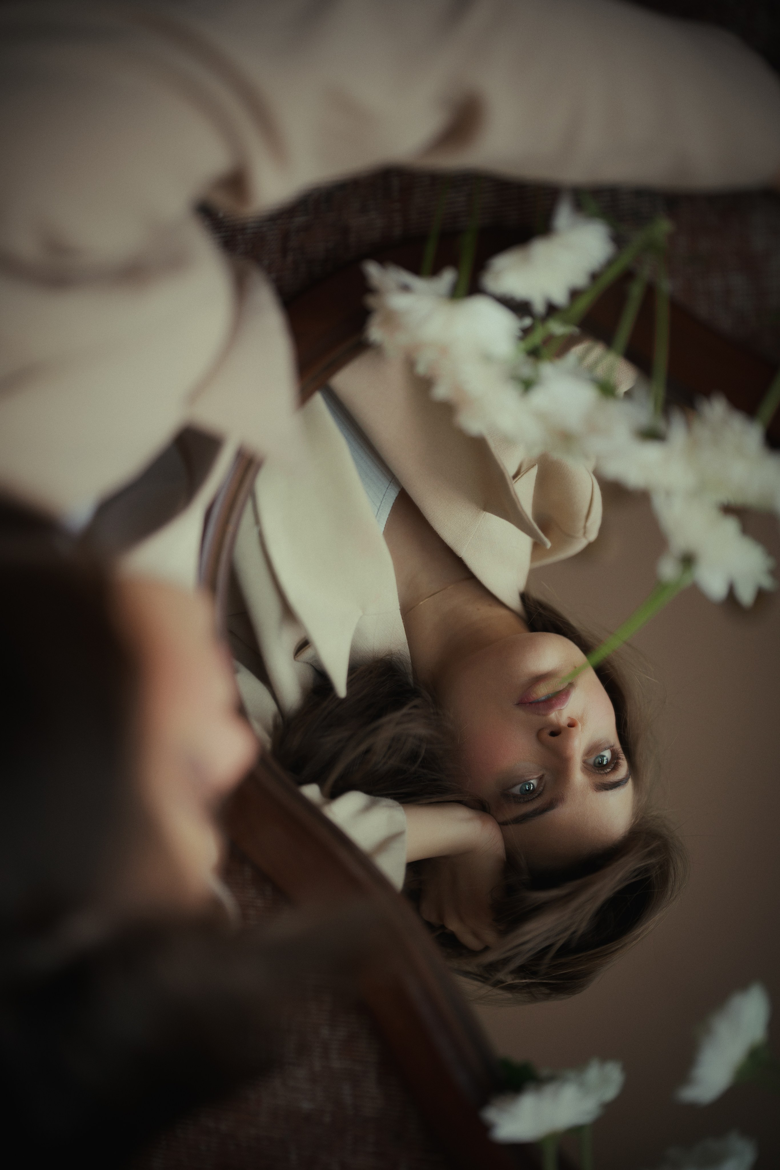 Dreamy editorial mirror portrait framed by white flowers, featuring warm tones and shallow depth of field by Mehran Hadad.