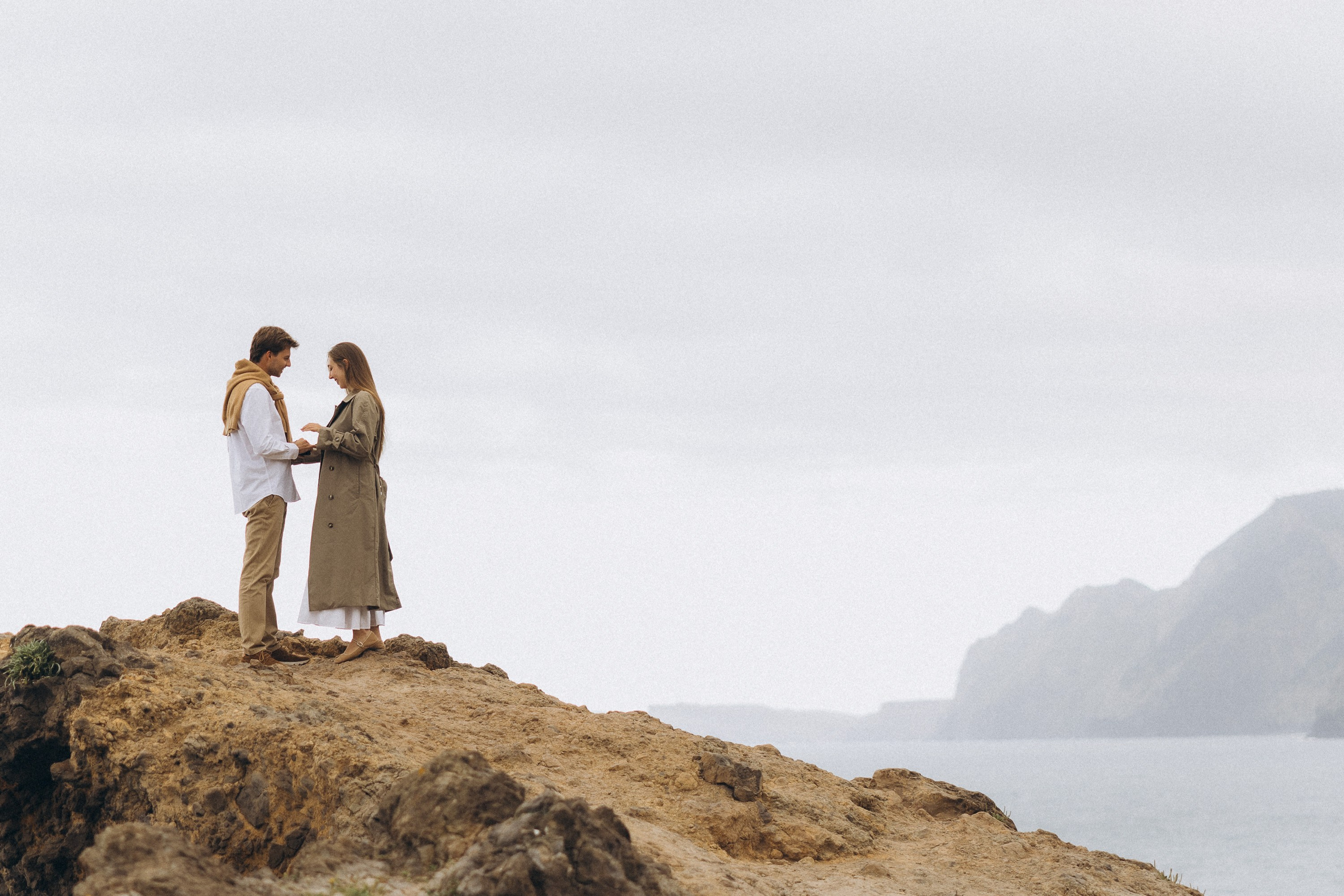 Beautiful engagement moment by the ocean in Madeira, Portugal, as one partner kneels to propose while waves crash in the background