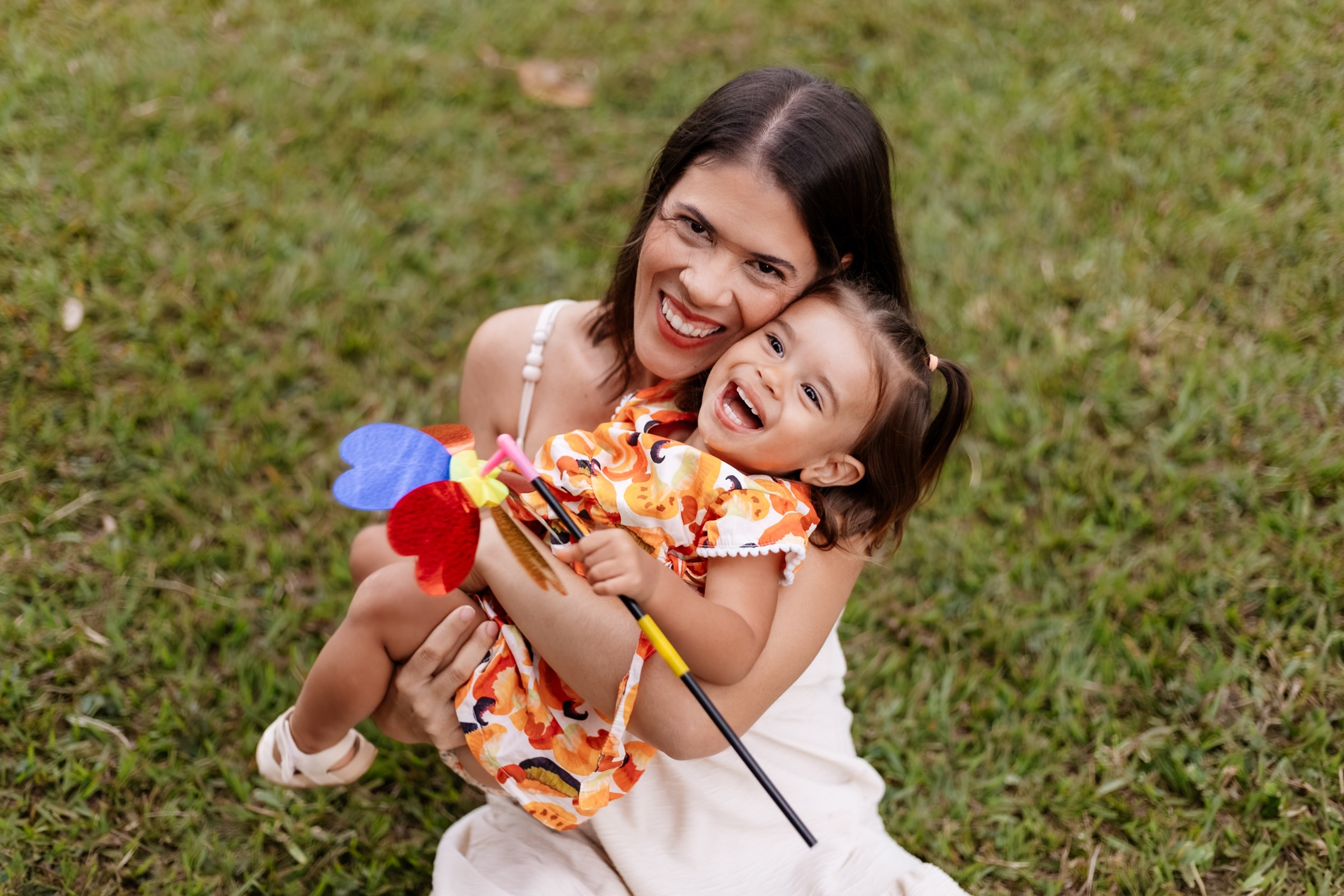 Mãe e filha brincando no gramado em ensaio de família