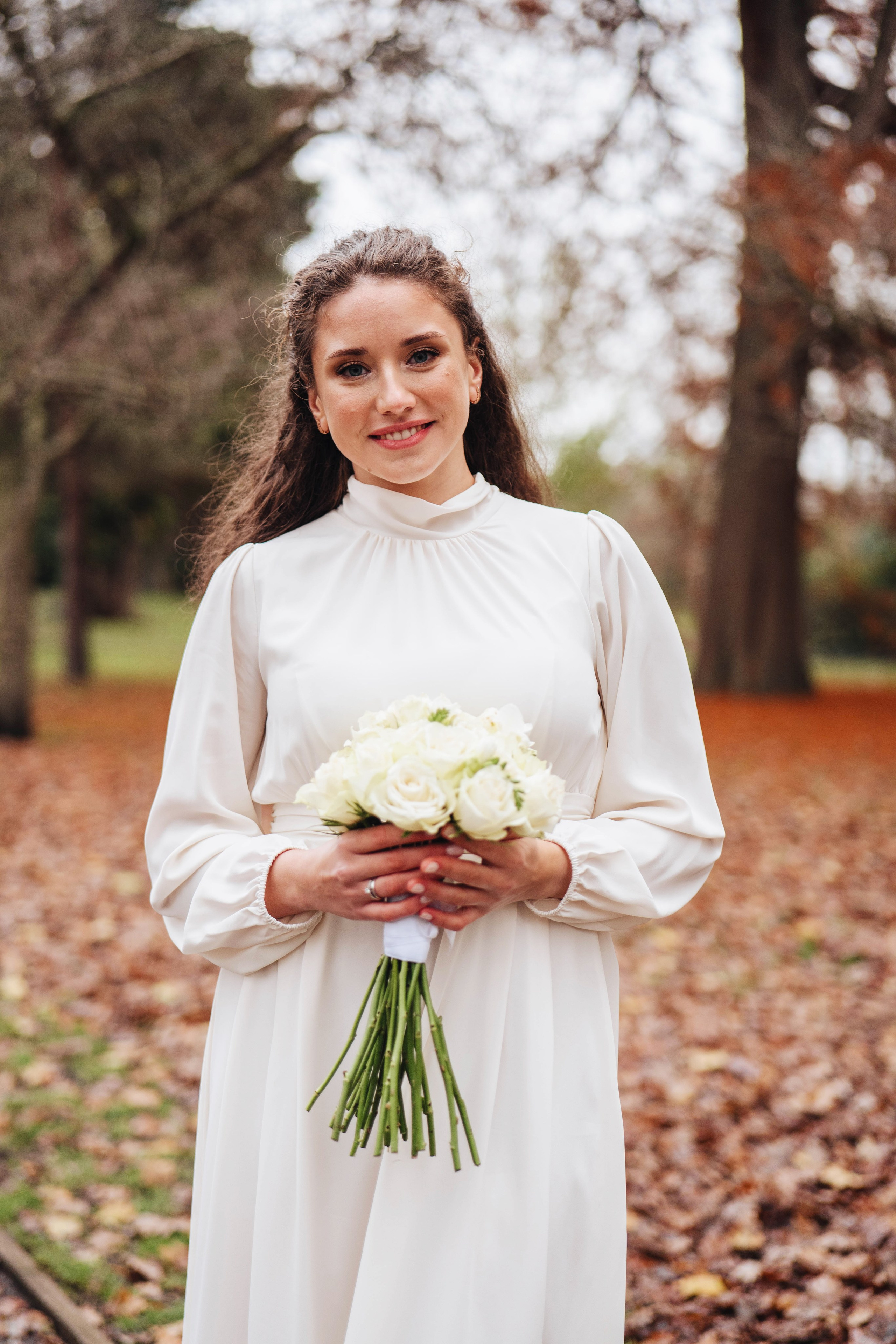 The bride walking along in an autumn park with a bouquet of flowers.