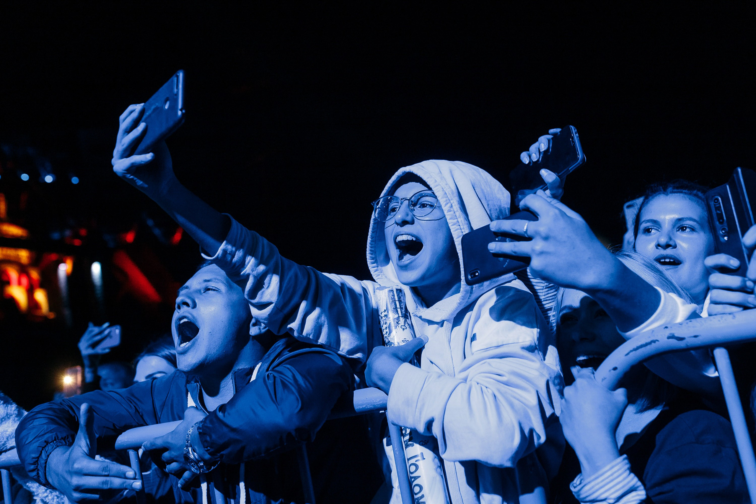 Audience cheering at concert under blue lights