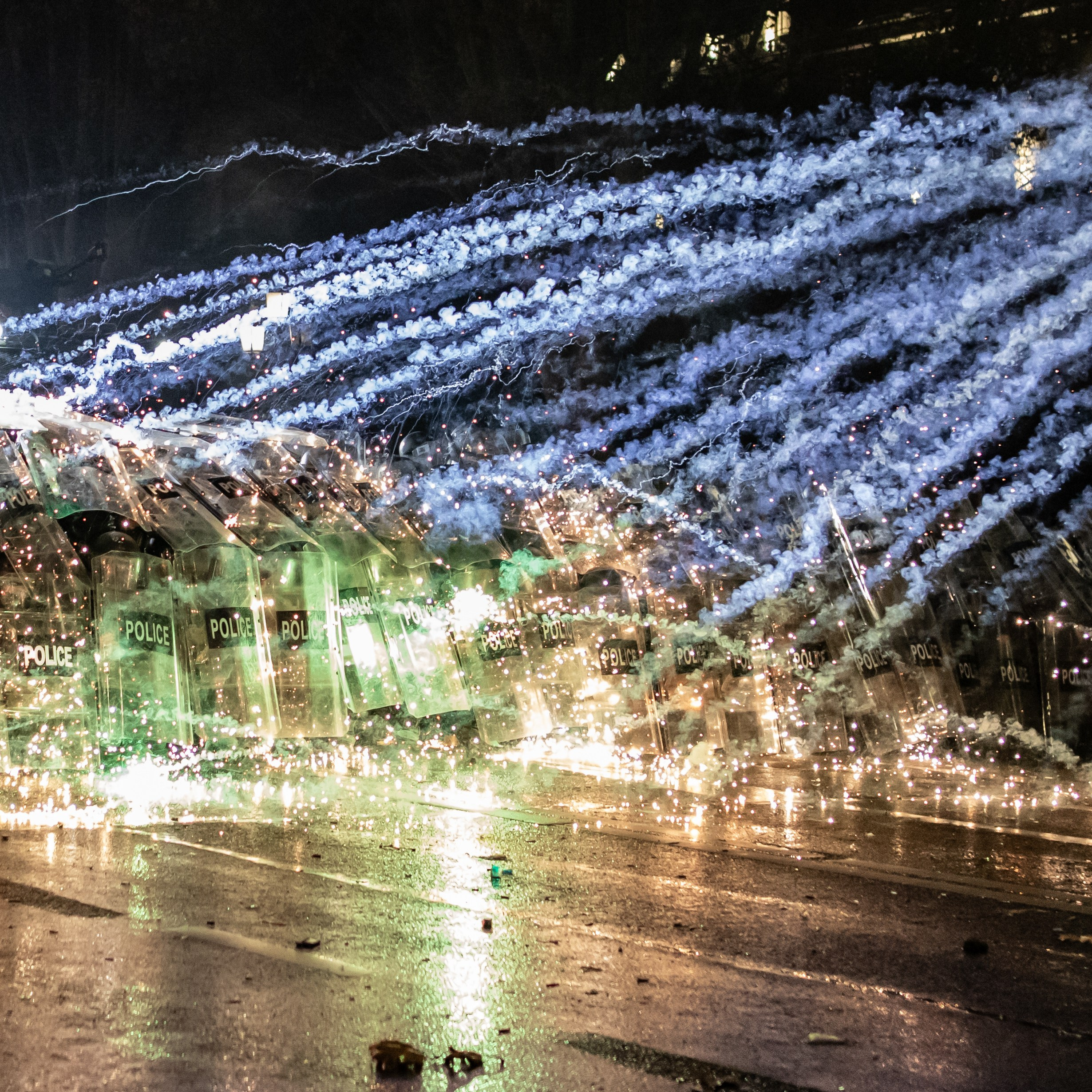 Les manifestants tirent des feux d’artifice sur les forces de l’ordre, protégées par leurs boucliers devant le Parlement.