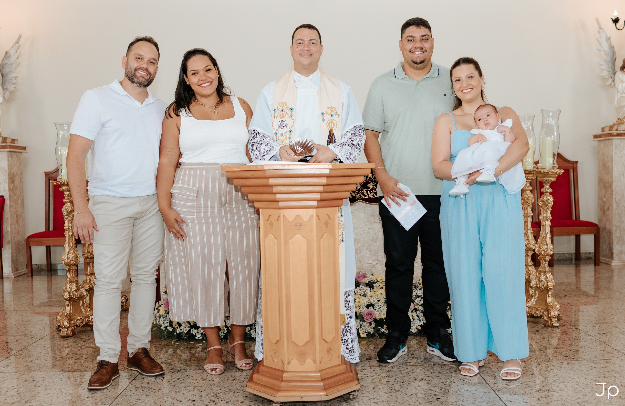 Família com bebê e sacerdote posando no altar.