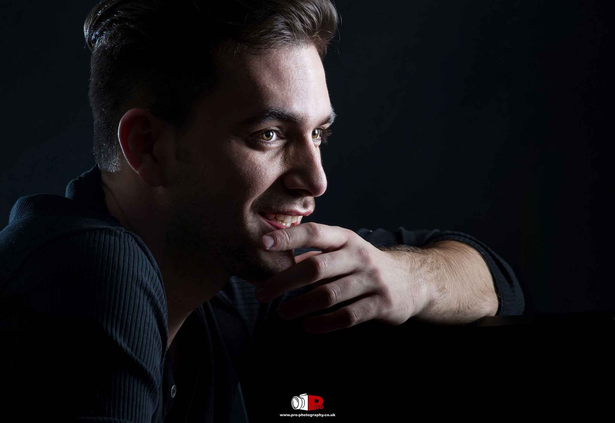 Close-up portrait of a thoughtful man illuminated by shadow lighting, showcasing artistic portrait photography.