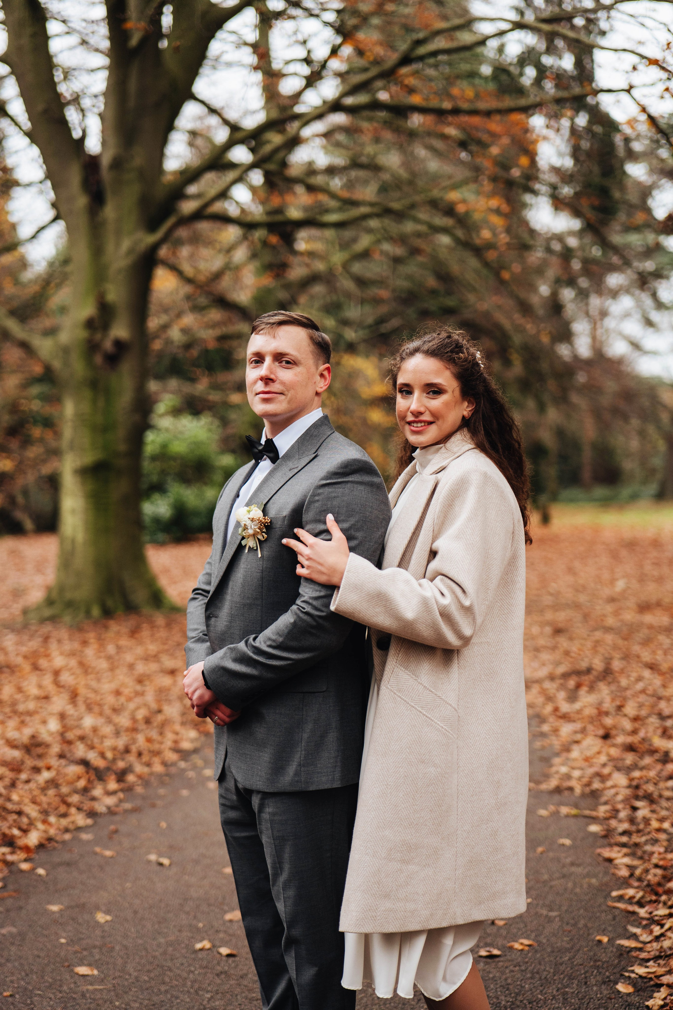 bride hugging groom from the back in the colourfull autumn park