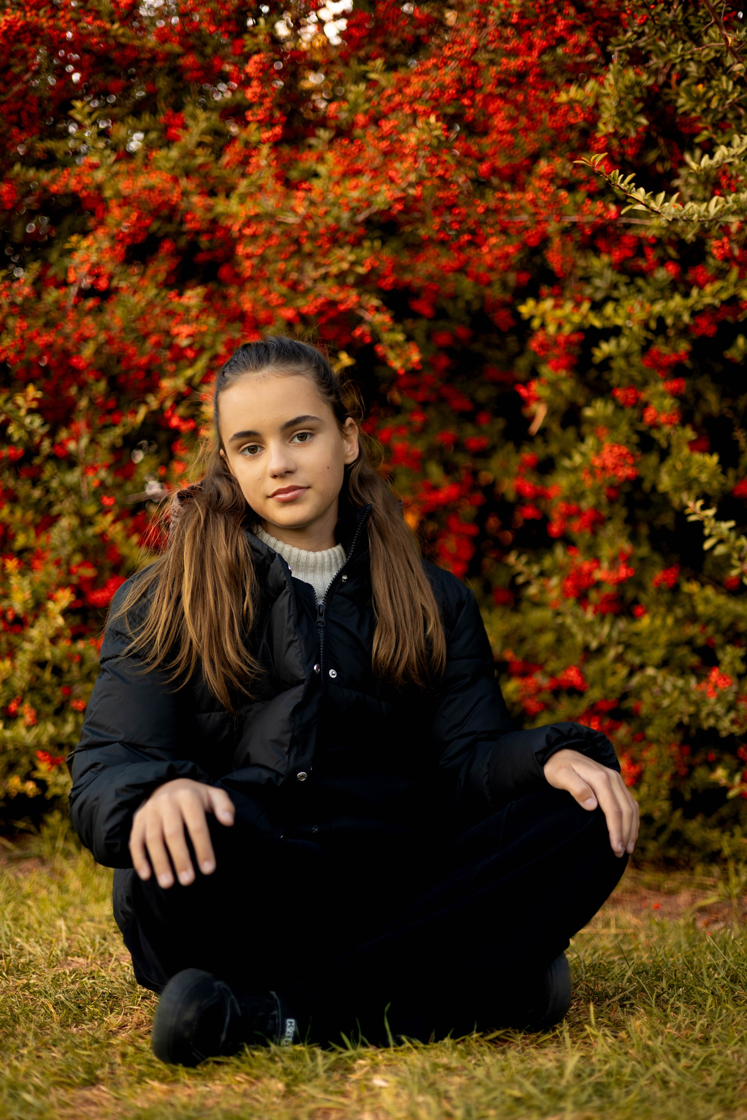 Портрет девушки в осеннем парке у куста с ярко-красными ягодами.