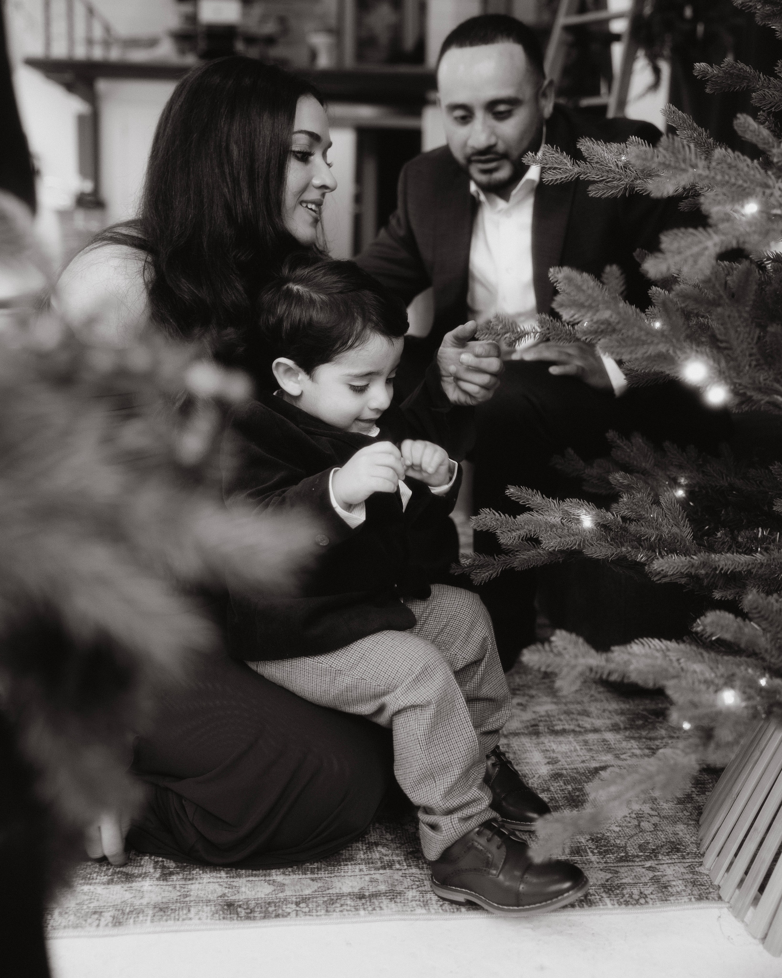Parents decorating Christmas tree with toddler during holiday photoshoot