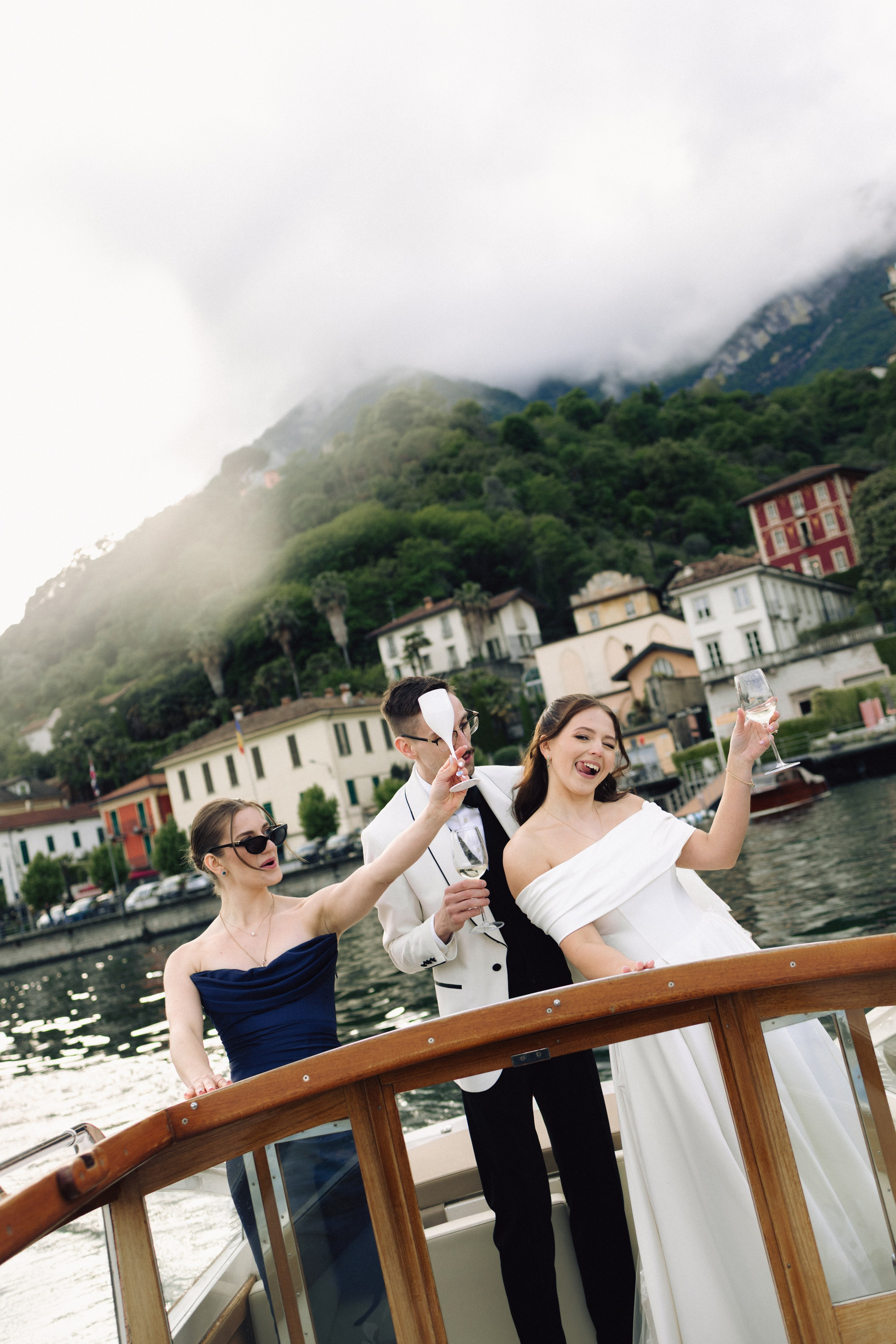 Bride and groom holding champagne glasses while enjoying a boat ride on Lake Como