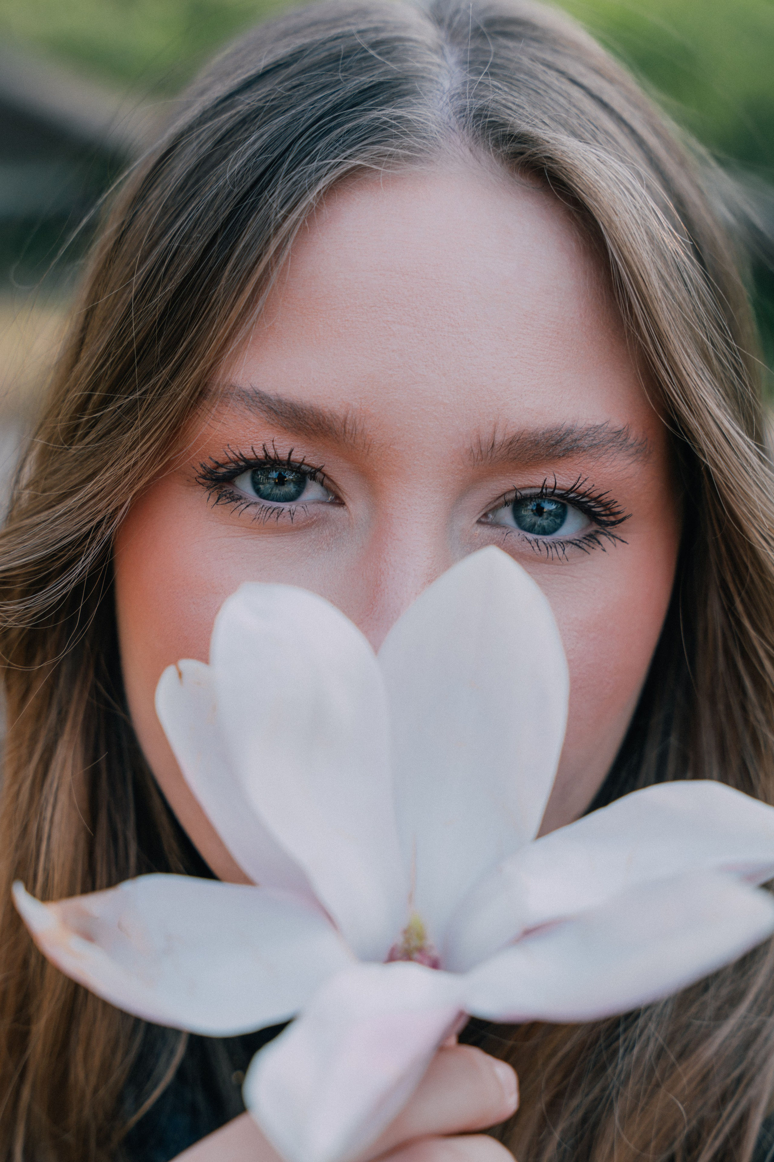 девушка закрывает половину лица цветком магнолии на фотосессии в Милане 