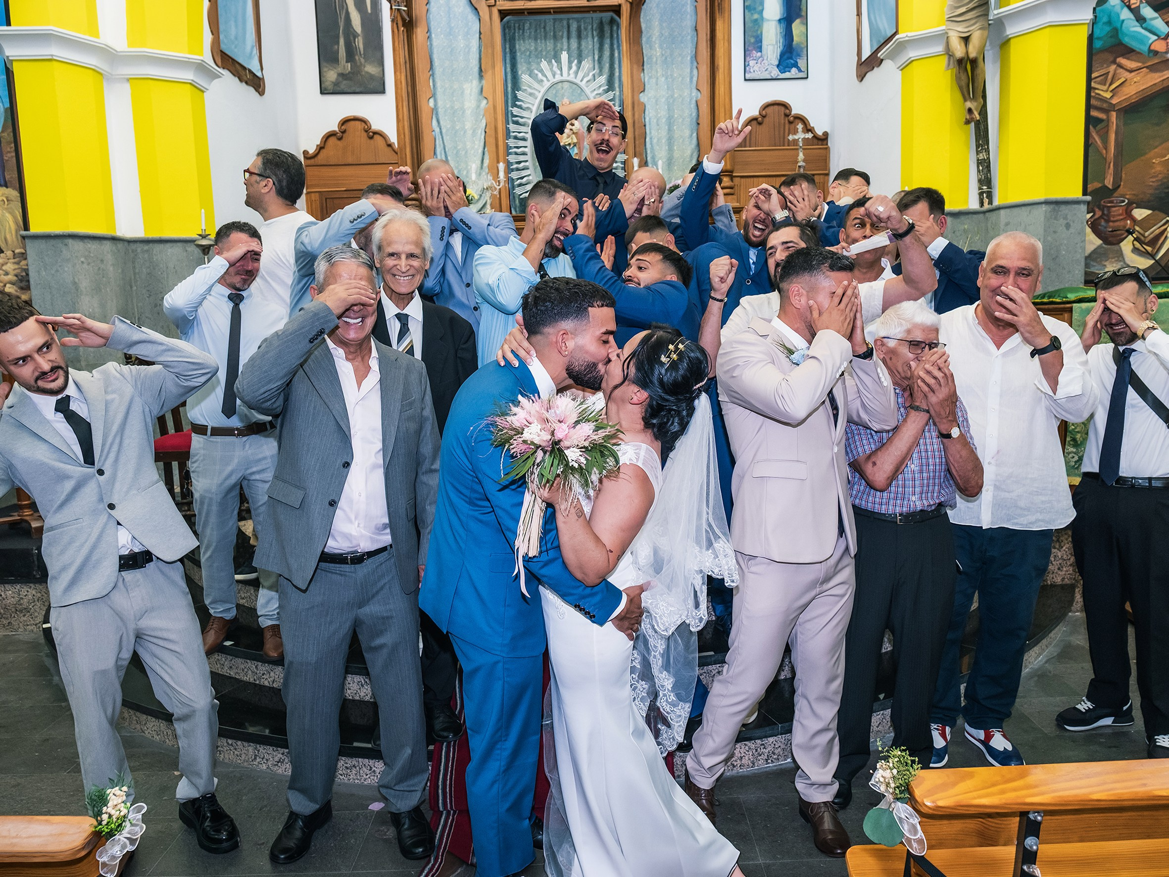 Los novios se besan al salir de la iglesia entre invitados celebrando