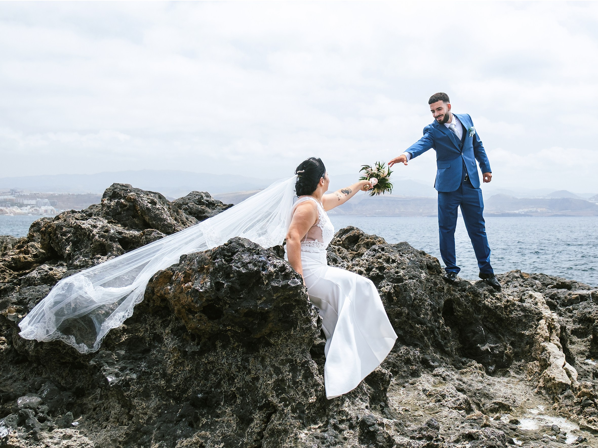El novio entrega el ramo a la novia sobre rocas volcánicas en Gran Canaria