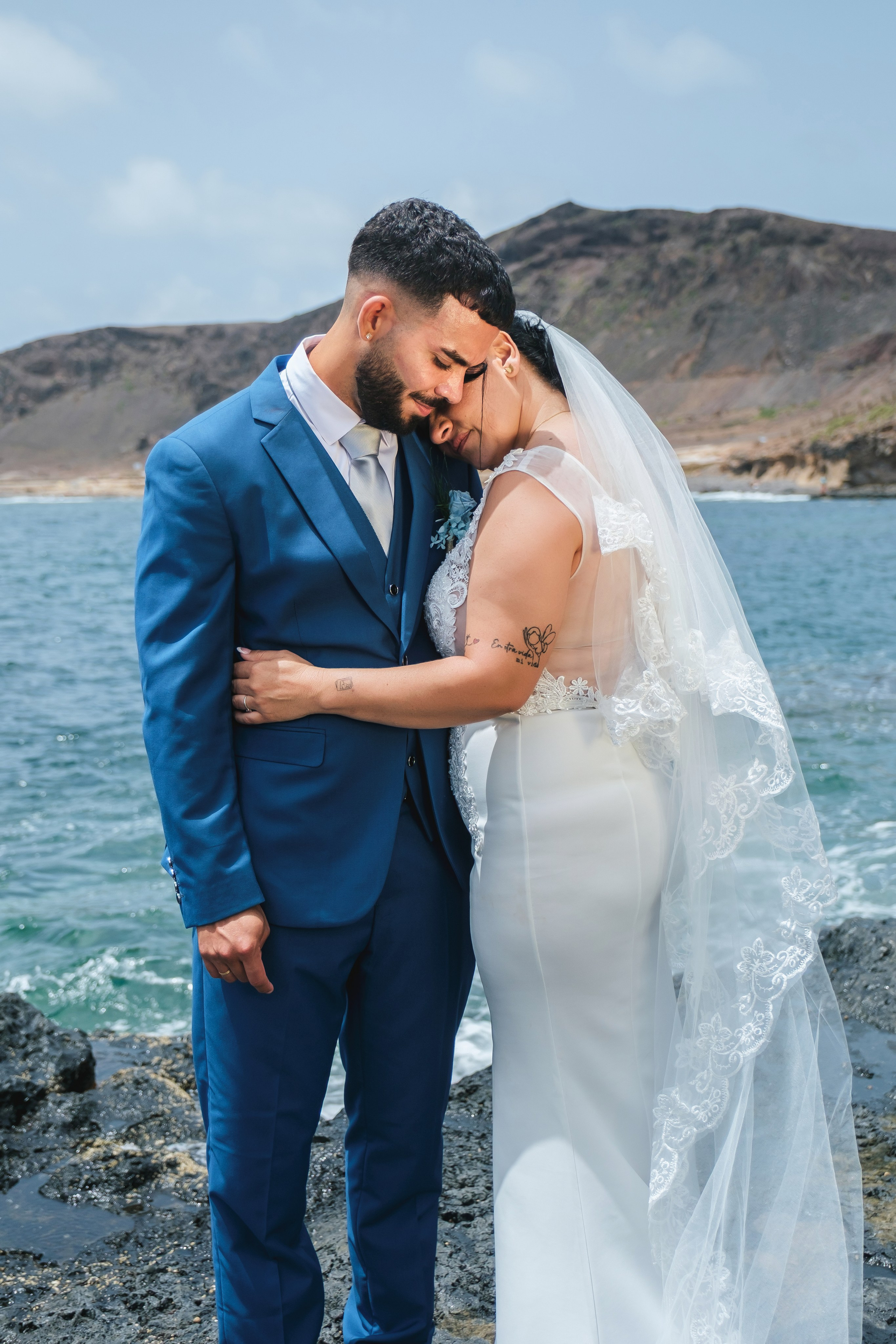 Novios abrazados frente al mar con los acantilados de Gran Canaria detrás