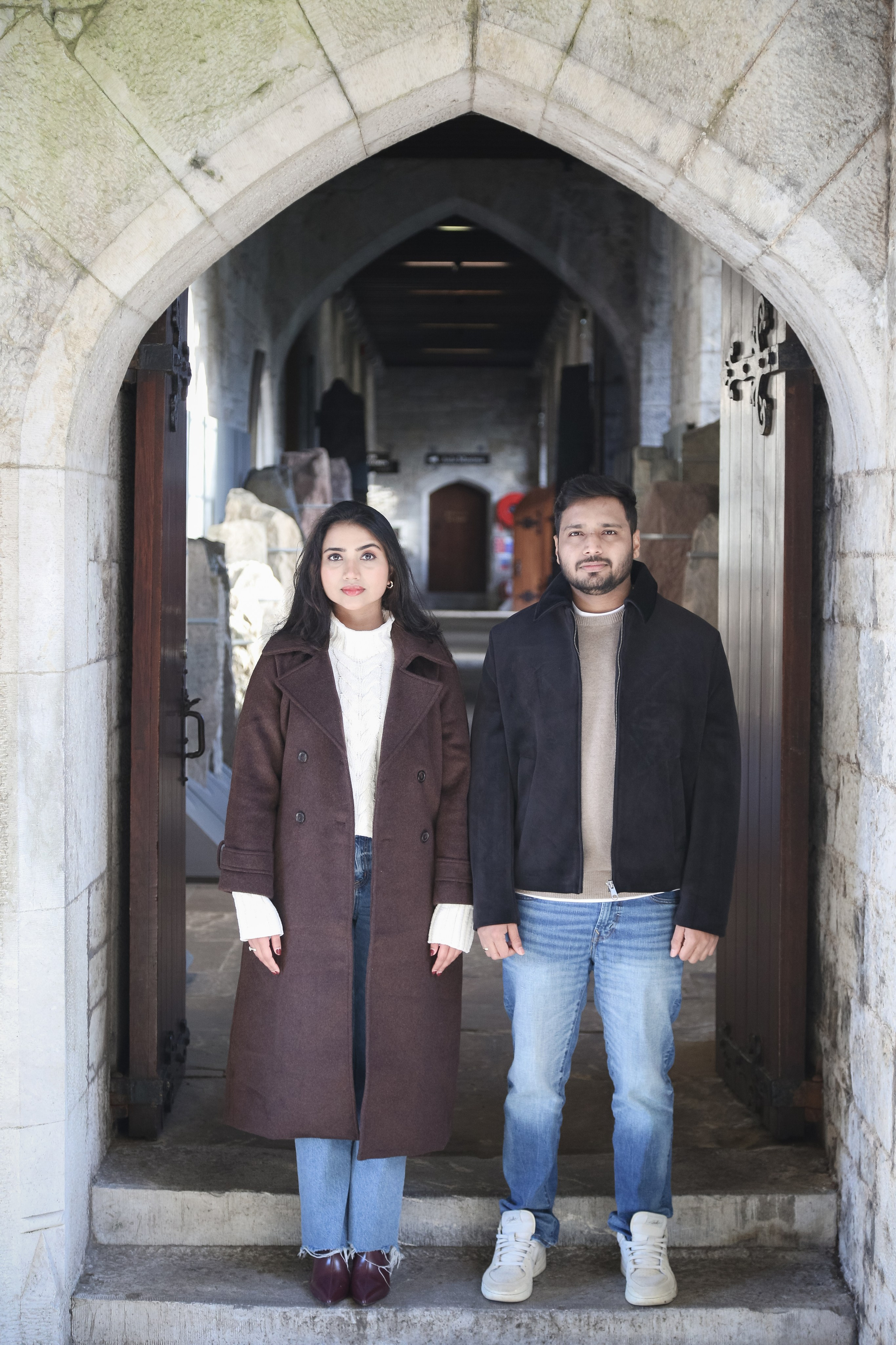 A strong and balanced portrait framed by historic stone architecture, highlighting presence, connection, and shared grounding.
