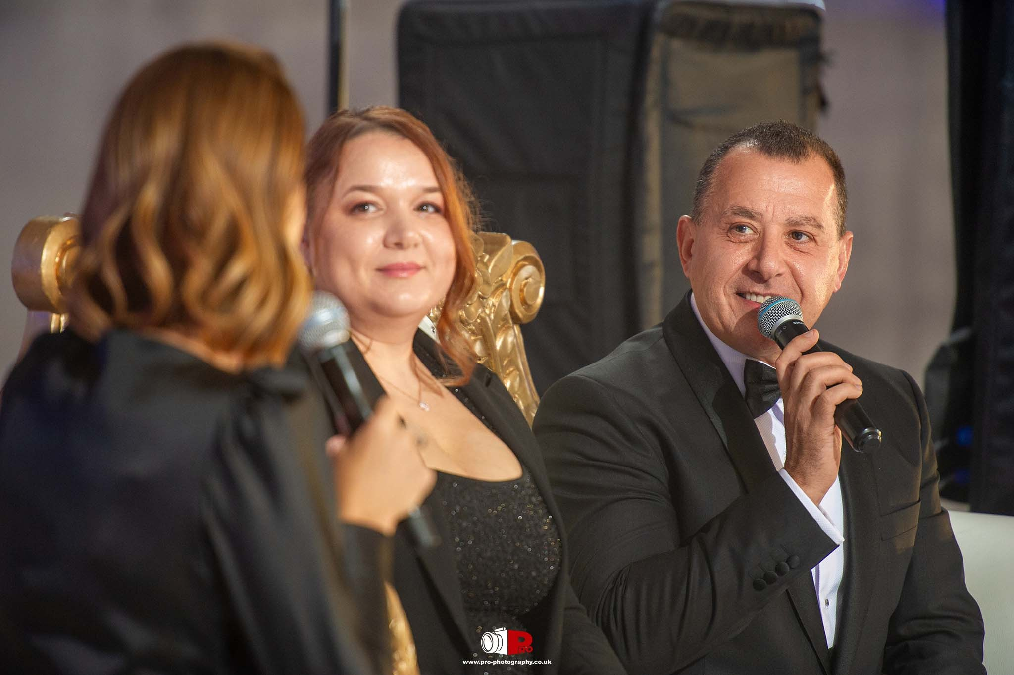A panel of speakers conversed during the MAD-Aid Gala, seated on luxurious gold chairs.
