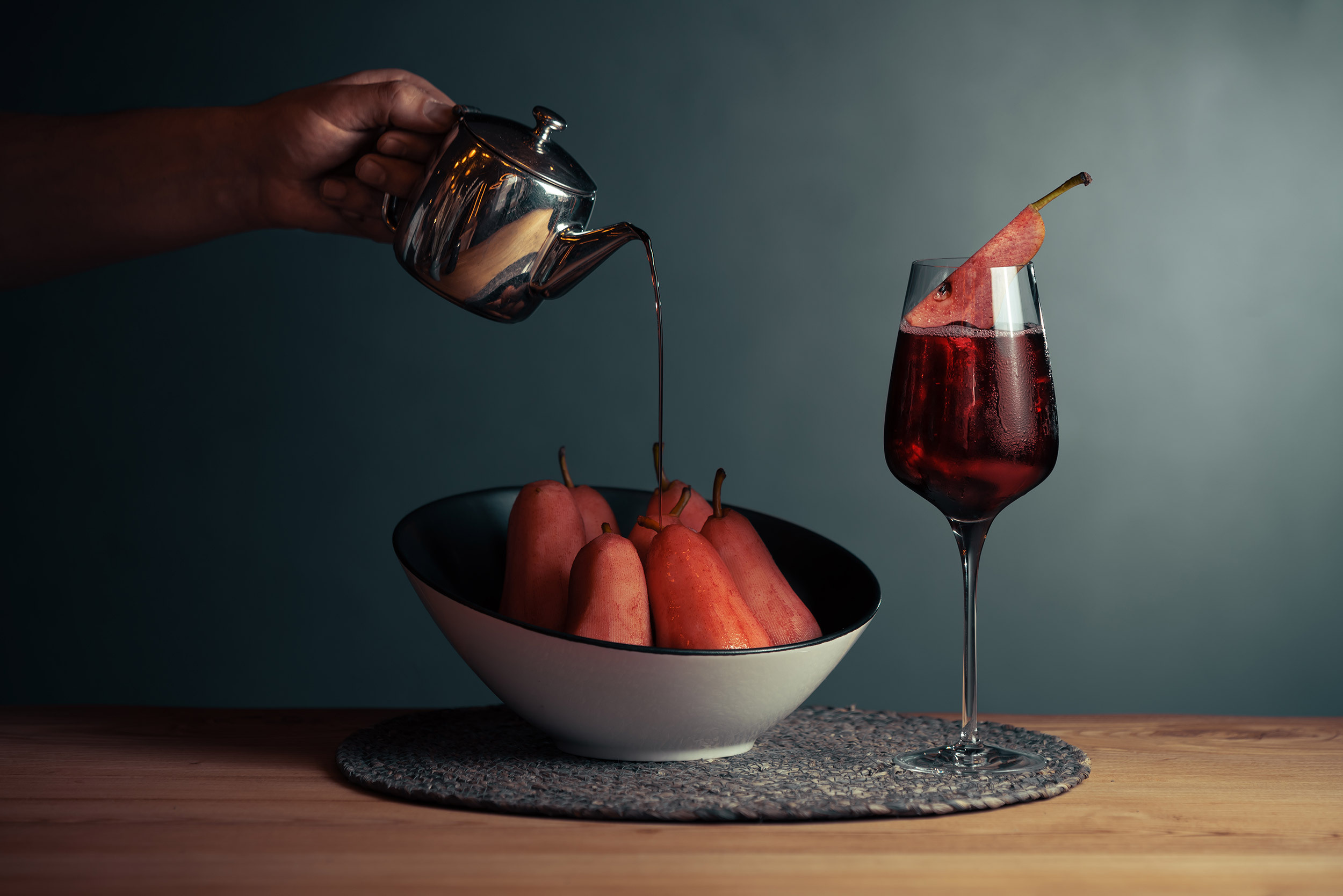 Pear and red wine drink served on a wooden table with fresh pears beside it