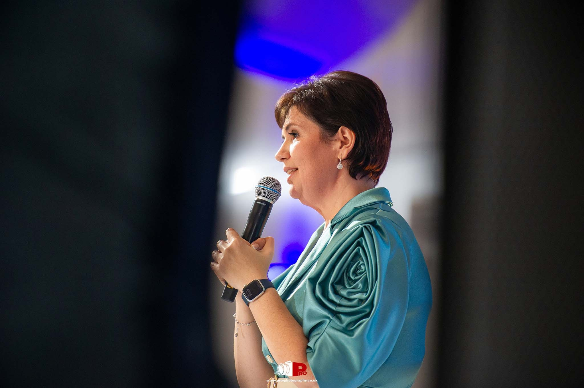Victoria Dunford, in a turquoise dress, is delivering a speech at the MAD-Aid Gala.