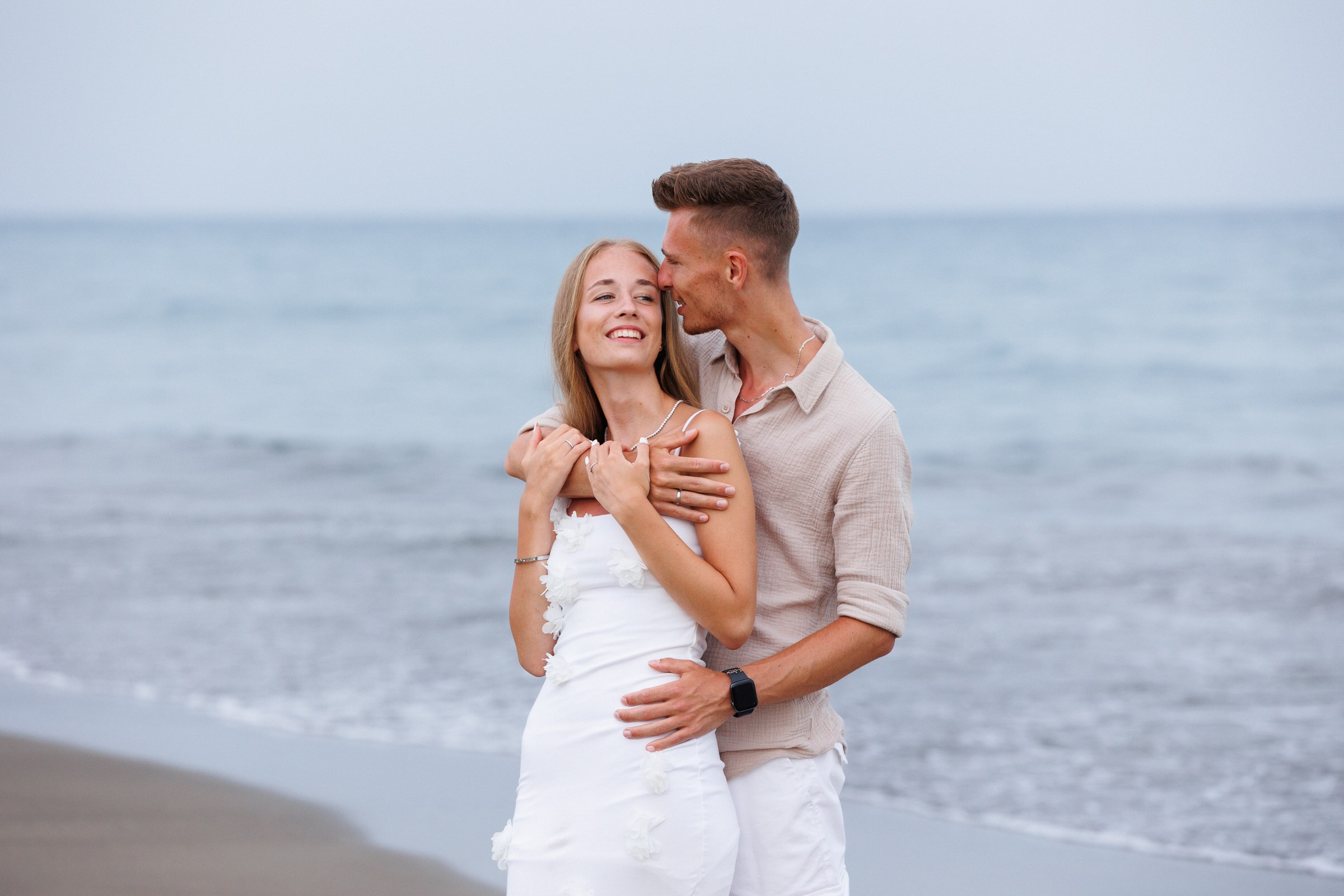 Relaxed beach portrait of a smiling woman enjoying her holiday, captured at golden hour by couples and vacation photographer Slavik Robtsenkov.