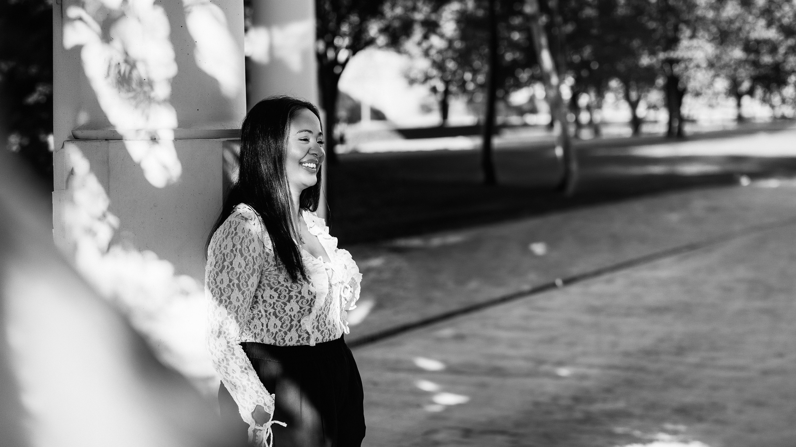 Женская портретная фотосессия в Валенсии, Испания: женщина улыбается, прислонившись к колонне.