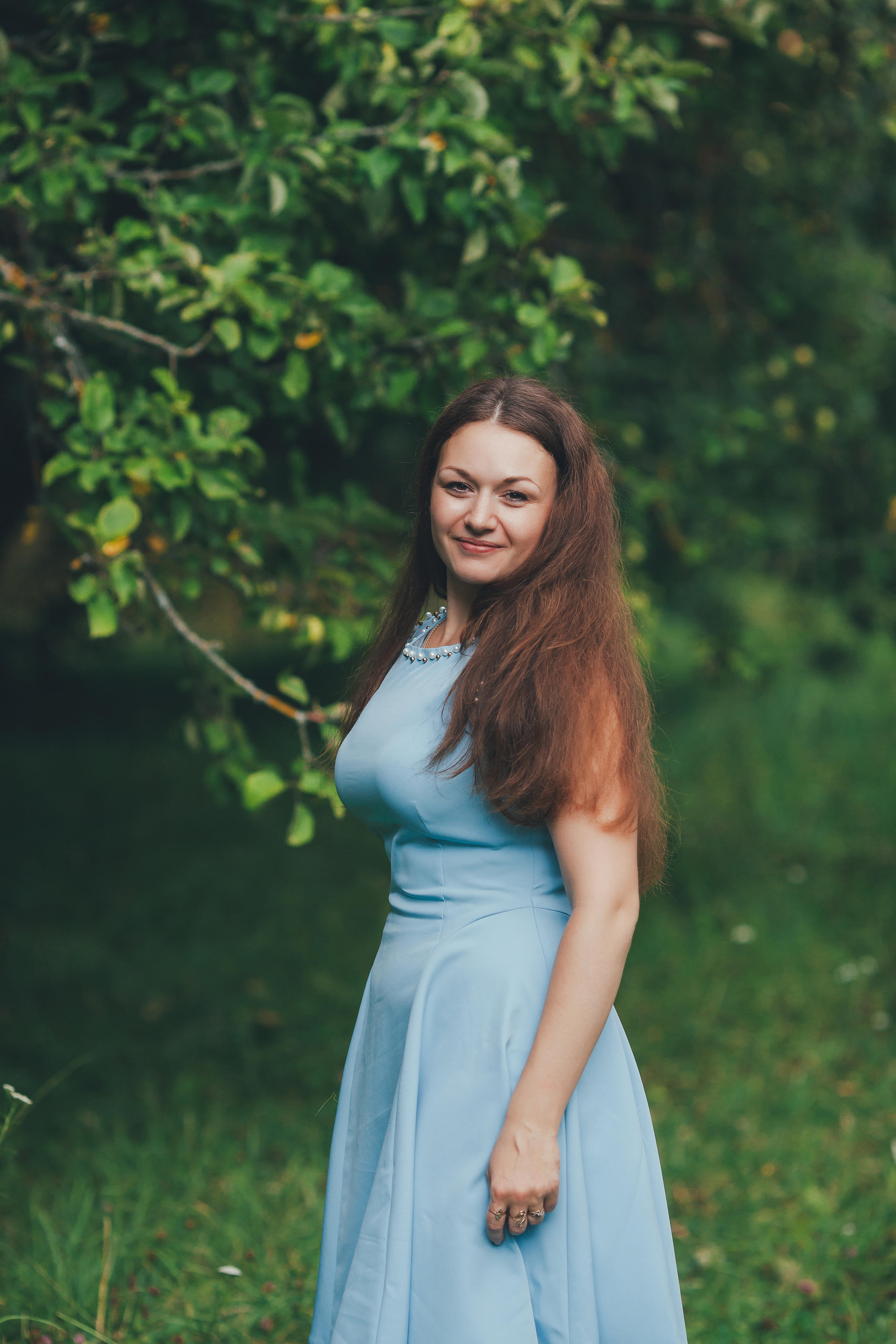 Красивая девушка в голубом платье счастливо улыбается