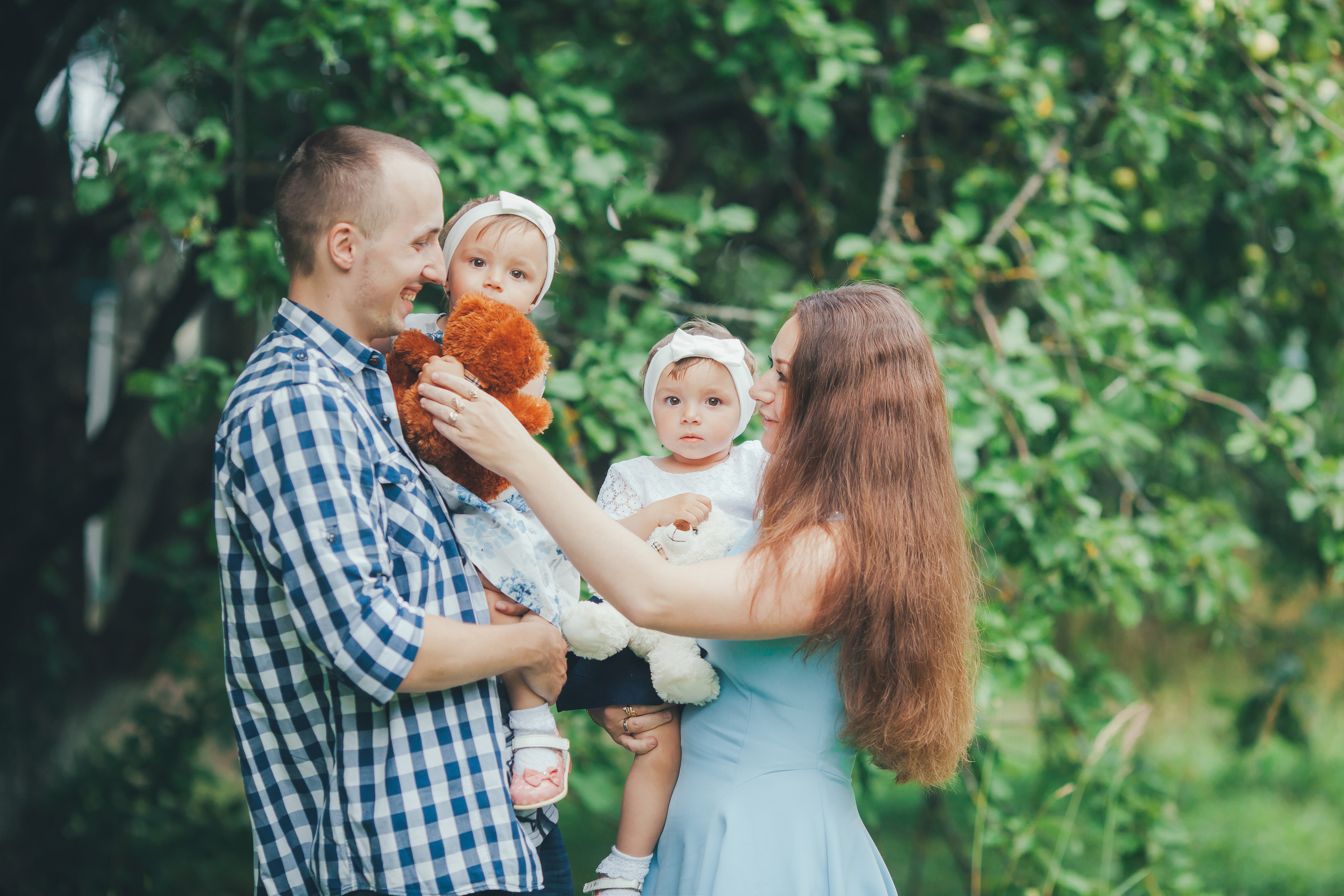 Счастливая семья с двойняшками в яблоневом саду.