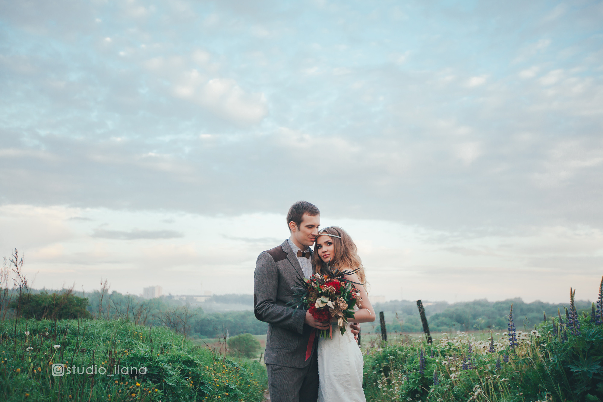 Жених и невеста на фоне облачного неба и шикарного поля.
